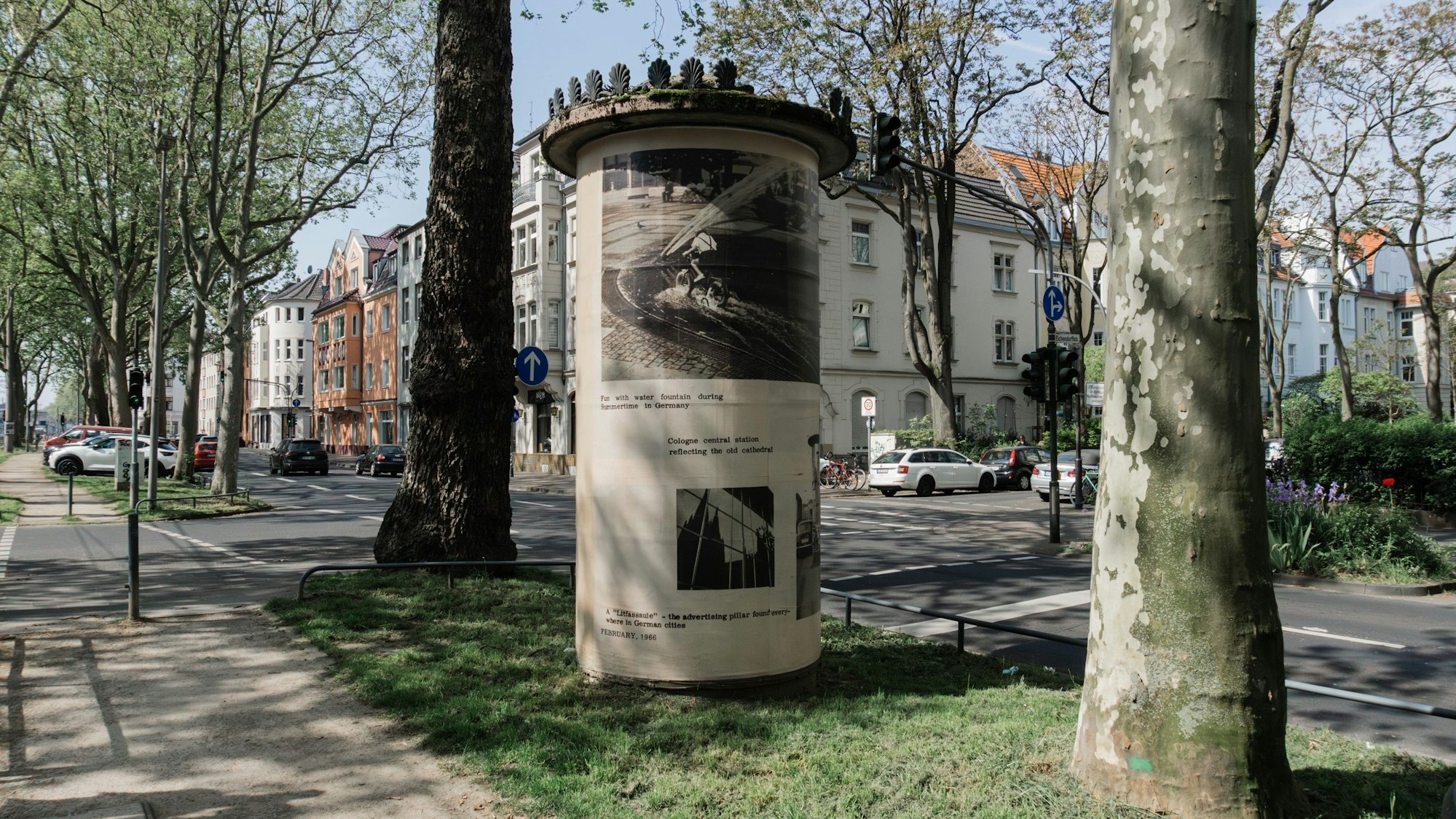 Auf einer Litfaßsäule sind Schwarz-/Weißbilder drauf zu sehen.