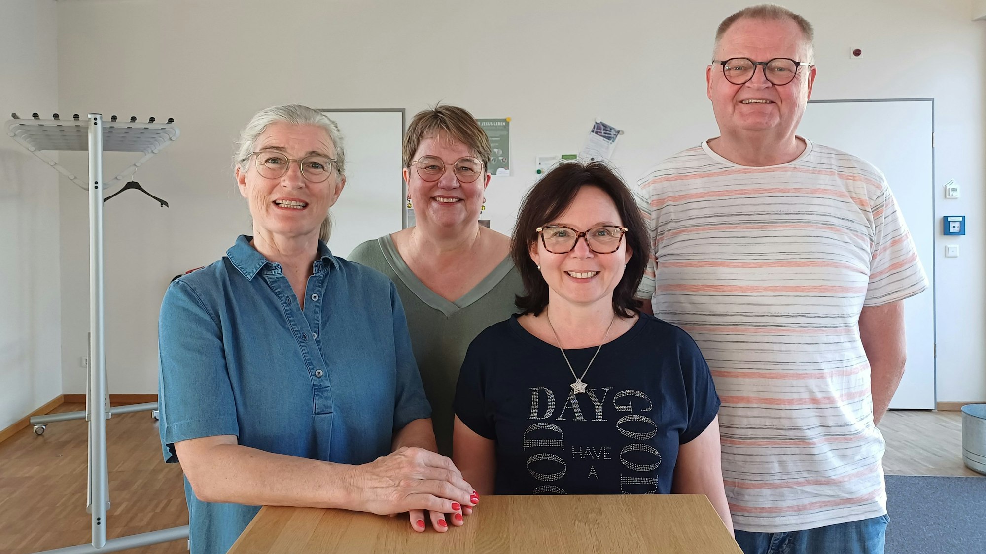 Drei Frauen und ein Mann stehen an einem Tisch.