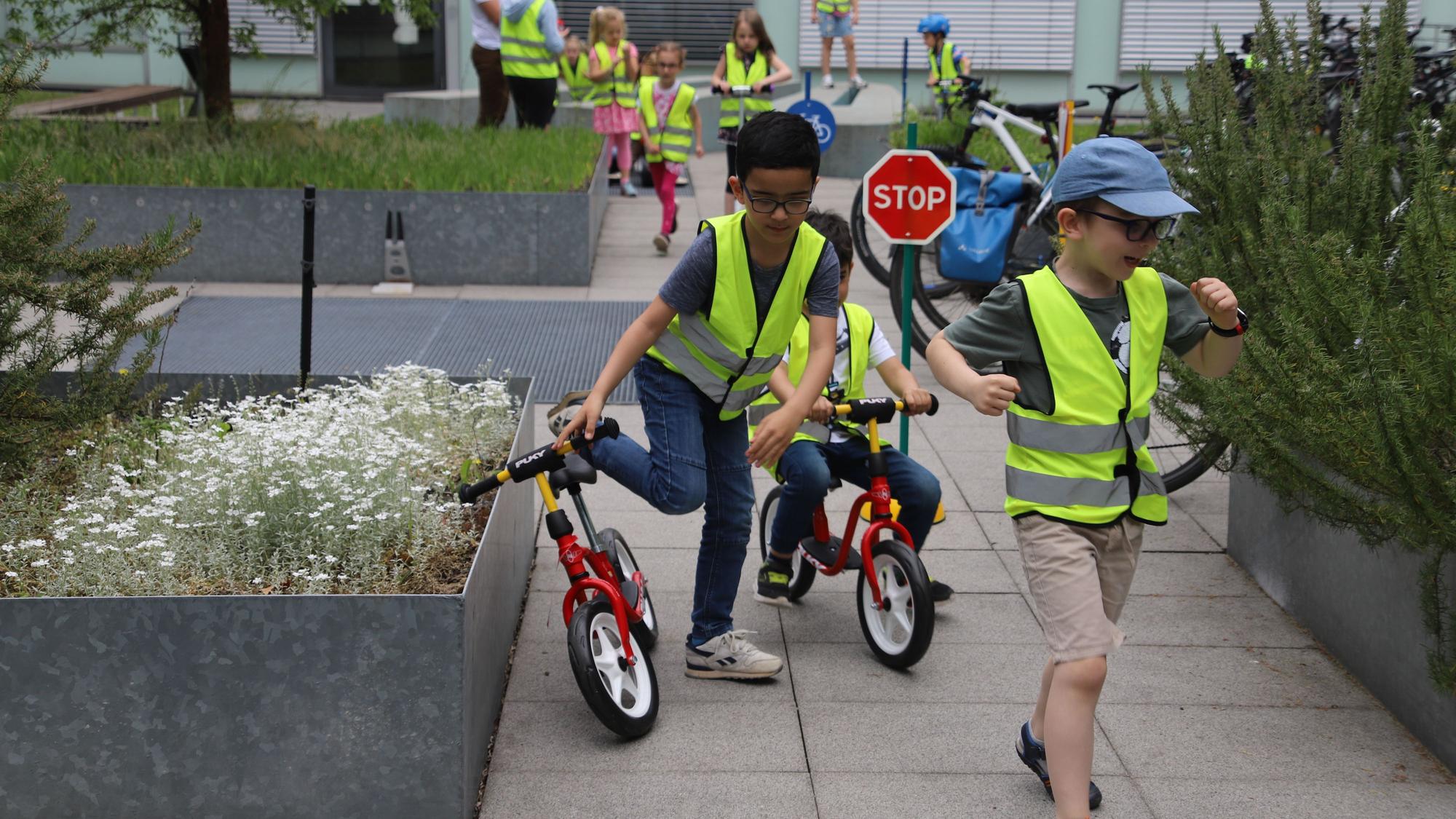 Kinder fahren mit Laufrädern durch den Innenhof der Polizeiwache.