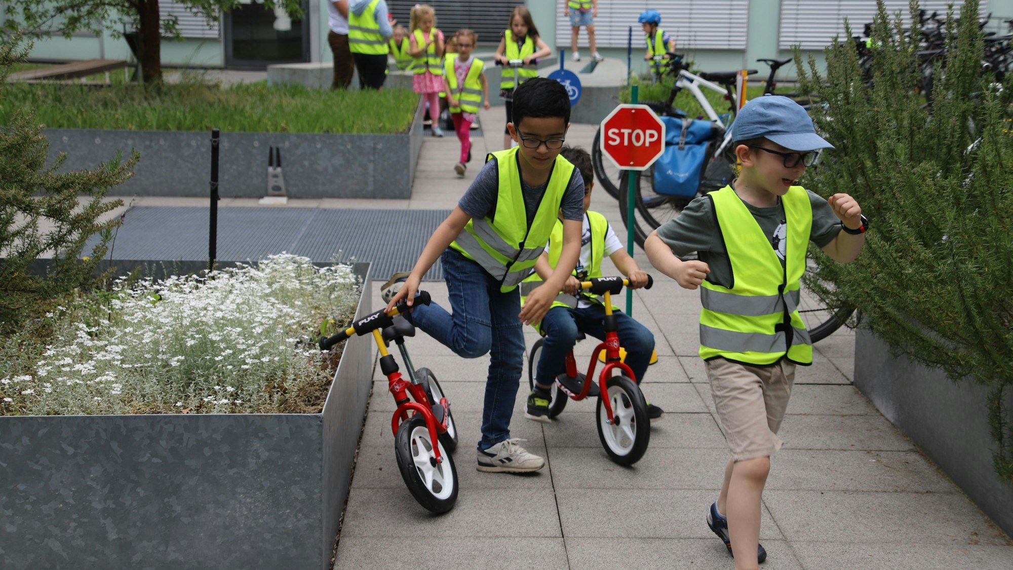 Kinder fahren mit Laufrädern durch den Innenhof der Polizeiwache.