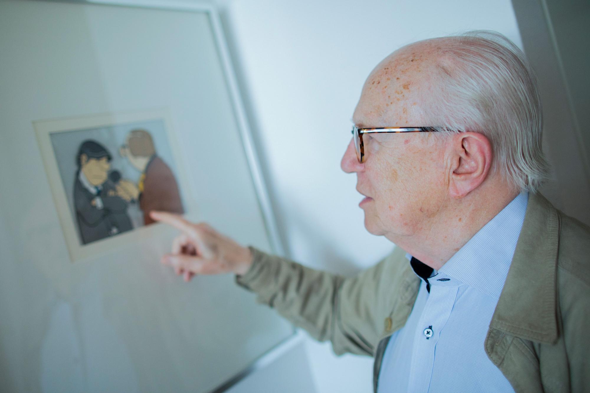 Friedrich Nowottny zeigt in seinem Flur auf eine Zeichnung von Loriot, die ihn (r) bei einem Interview mit dem damaligen Bundeskanzler Helmut Schmidt (SPD) zeigt.