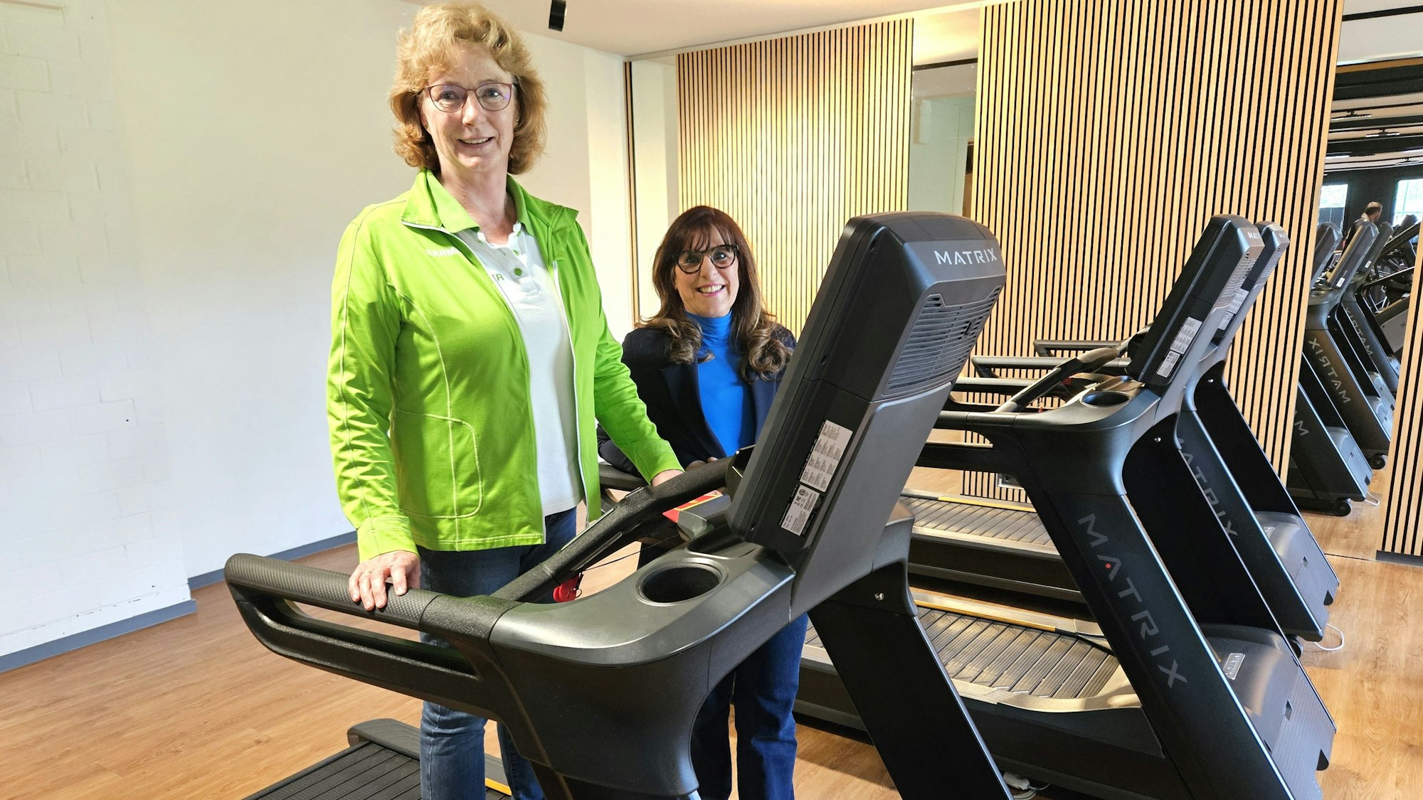 Petra Vossen steht auf einem Laufband und Petra Schumacher-Hendus dahinter.