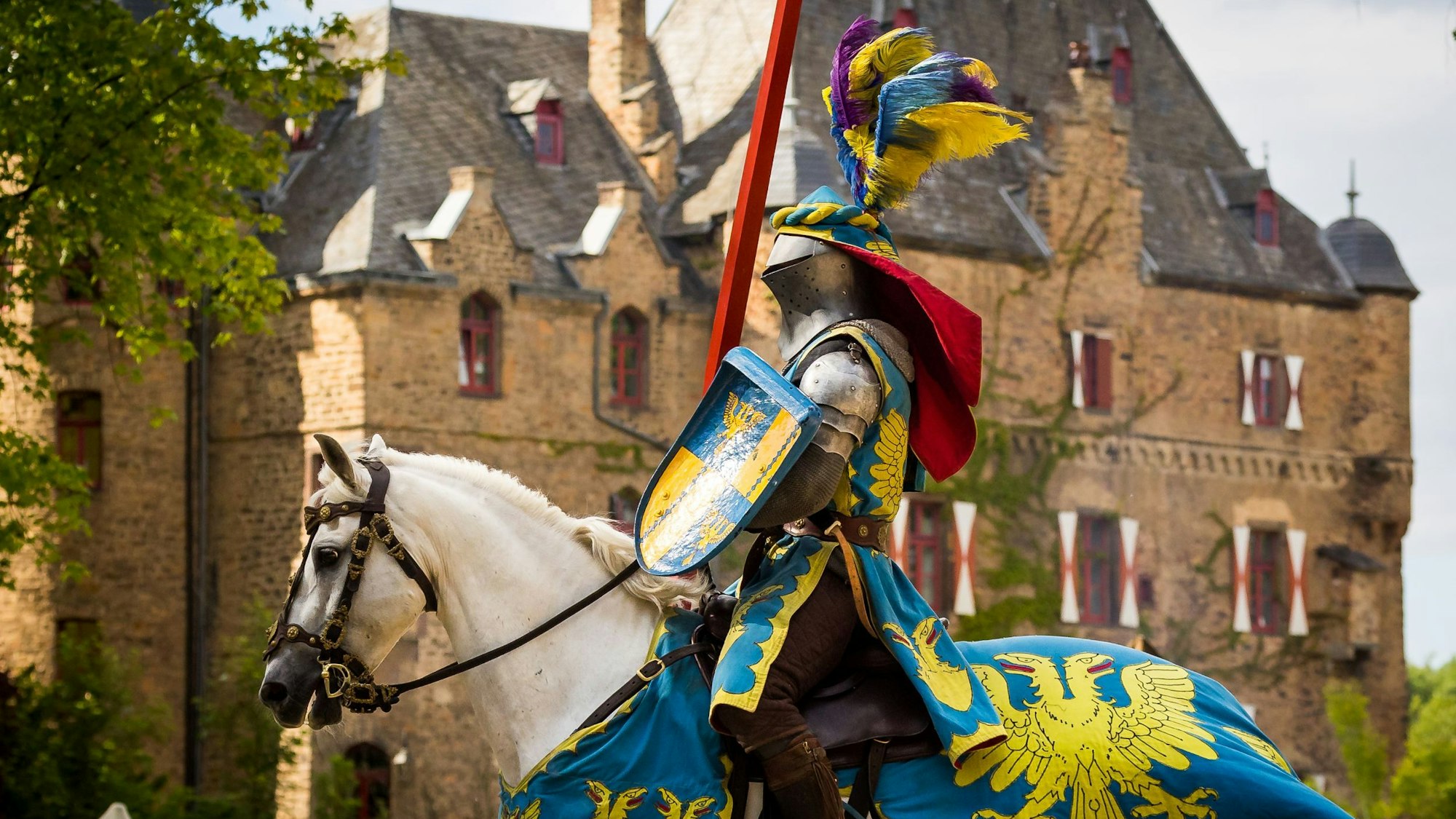 Ritter in Rüstung auf einem Pferd vor Burg Satzvey