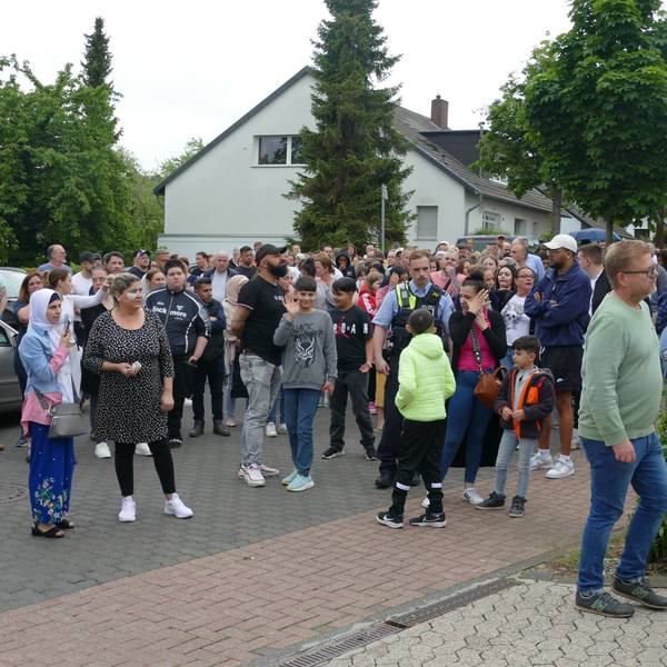 Eine größere Gruppe von Eltern und Angehörigen steht vor der Schule.