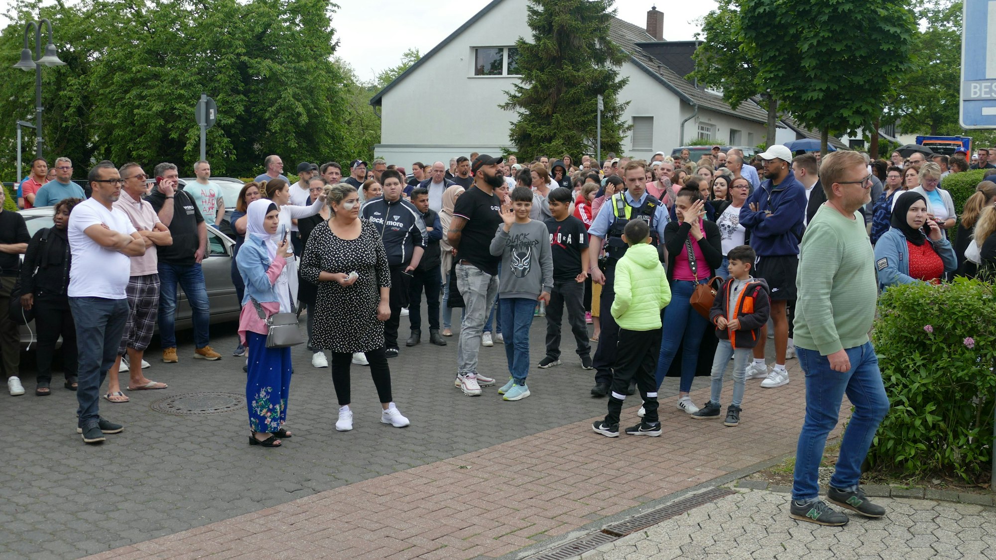 Eine größere Gruppe von Eltern und Angehörigen steht vor der Schule.