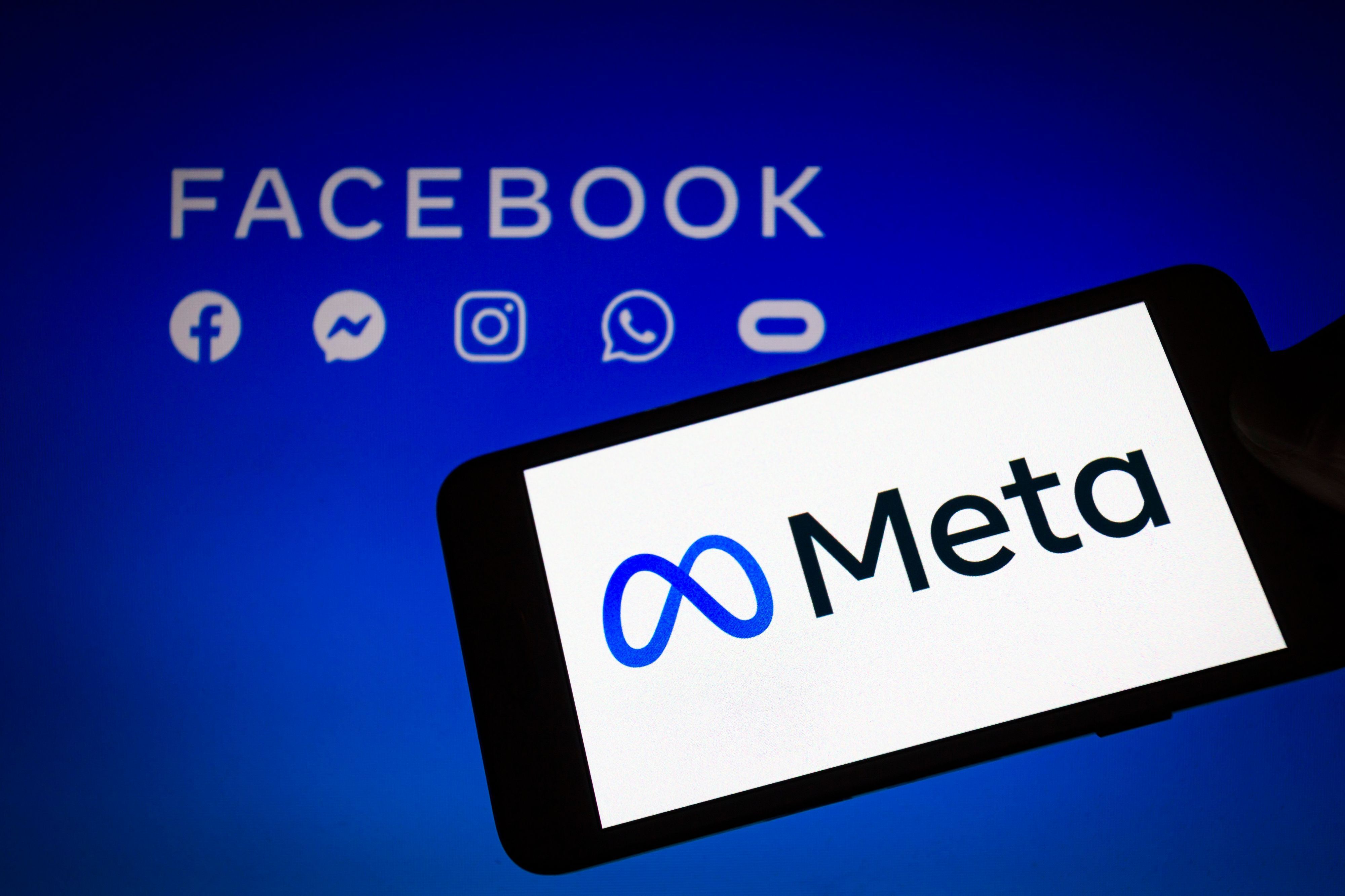 Das Logo von Meta, der Dachmarke des Facebook-Konzerns, wird auf einem Smartphone angezeigt, im Hintergrund sind die Logos von Facebook, Messenger, Instagram, Whatsapp und Oculus zu sehen.