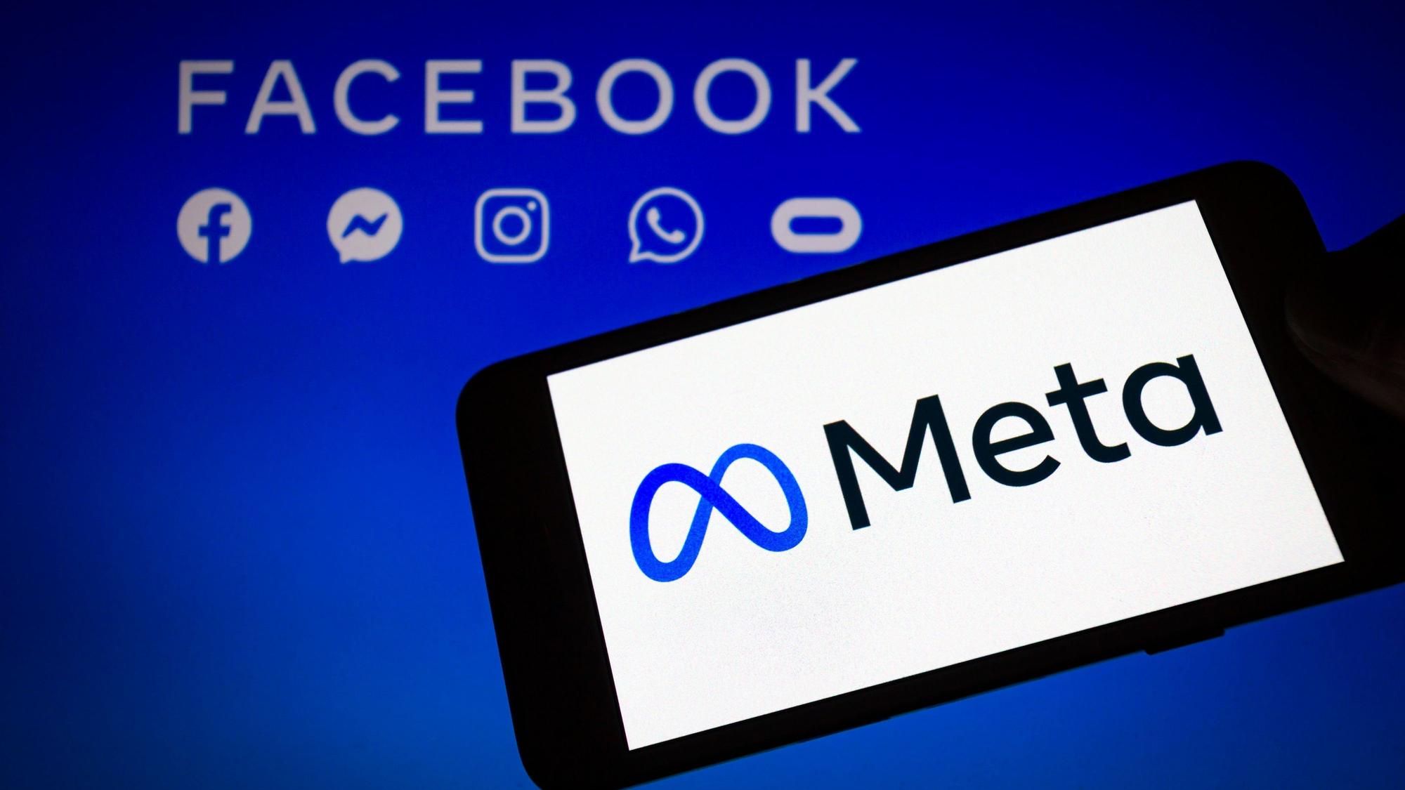 Das Logo von Meta, der Dachmarke des Facebook-Konzerns, wird auf einem Smartphone angezeigt, im Hintergrund sind die Logos von Facebook, Messenger, Instagram, Whatsapp und Oculus zu sehen.