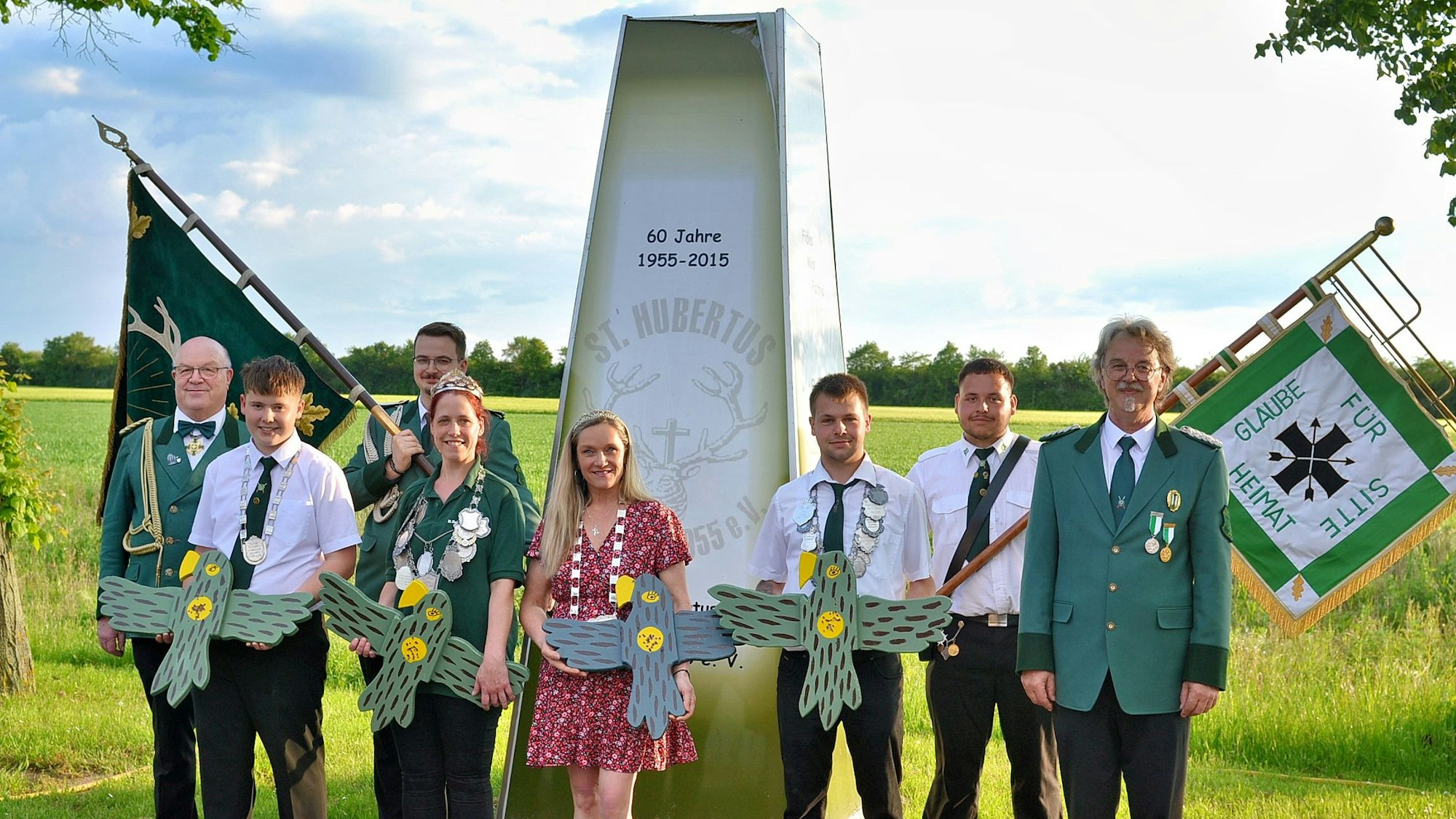 Die neuen Majestäten präsentieren ihre Trophäen, flankiert von Repräsentanten und Fahnenträgern des Schützenvereins.
