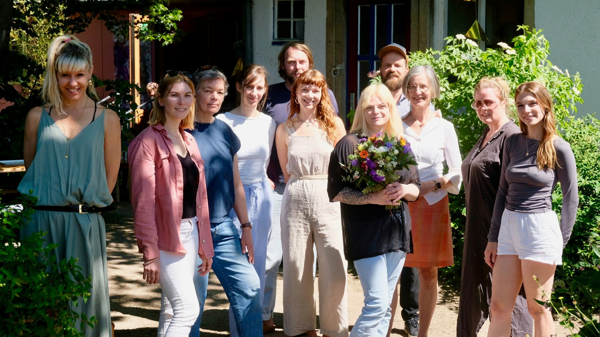 Anna Theusch mit einem Blumenstrauss von Gratulantin Cornelia Weitekamp (3.v.r.) ihrem Team und Mitgliedern vom Vereinsvorstand des Universitätskindergarten.