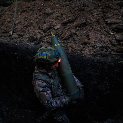Ein ukrainischer Soldat der 148. separaten Artilleriebrigade der Luftangriffskräfte der Streitkräfte der Ukraine trägt eine Granate, während er sich mit Kameraden darauf vorbereitet, eine leichte Schlepphaubitze vom Typ M777 auf russische Stellungen abzufeuern. (Symbolbild)