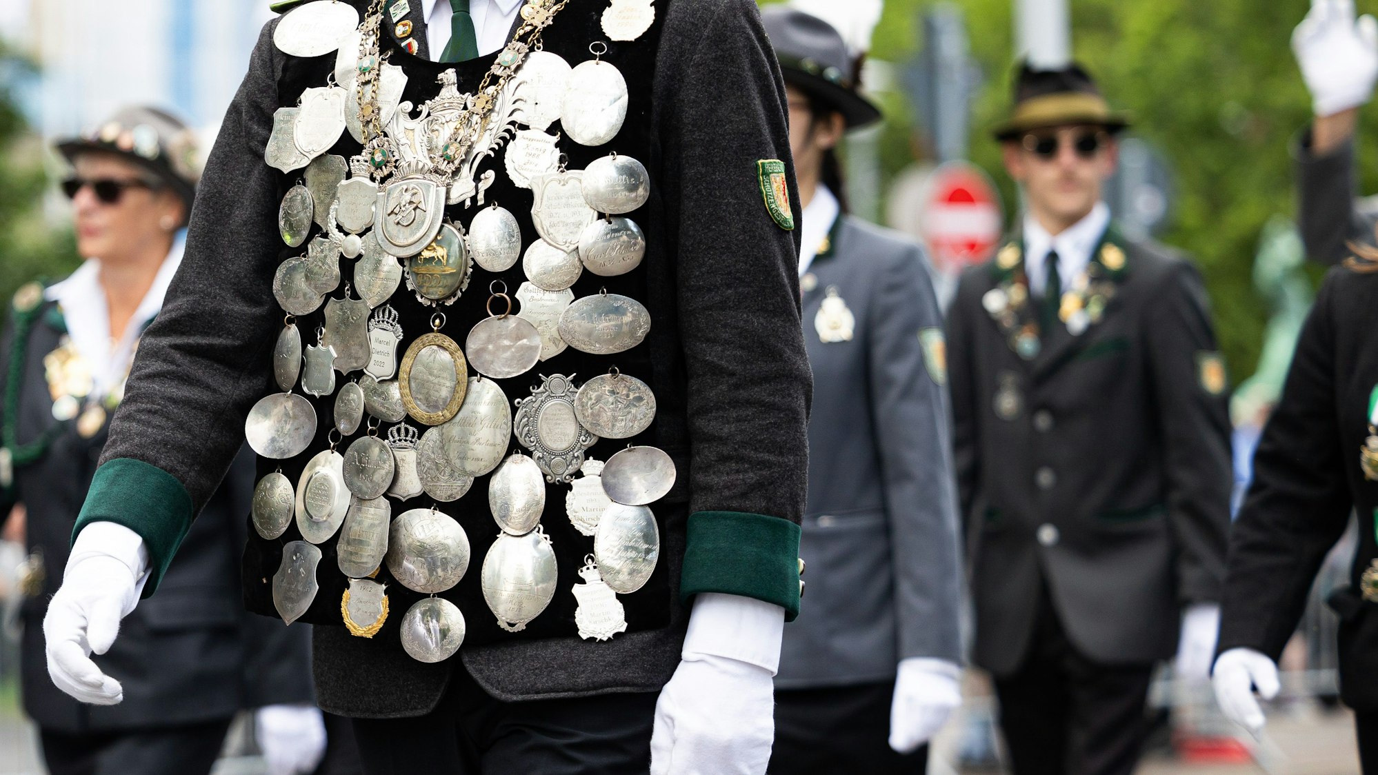 Ein Teilnehmer vom Schützenausmarsch trägt verschiedene Orden auf seiner Uniform und läuft durch die Innenstadt von Hannover.