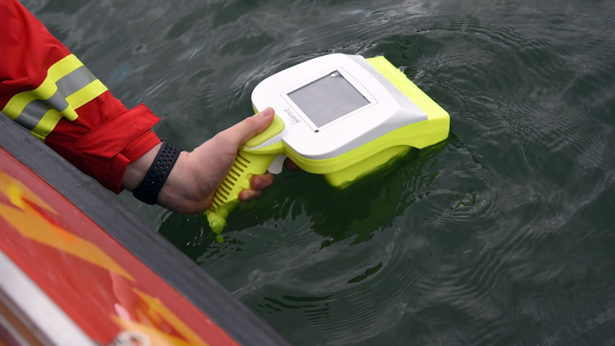 Ein Wasserretter hält ein Sonargerät über die Wasseroberfläche.