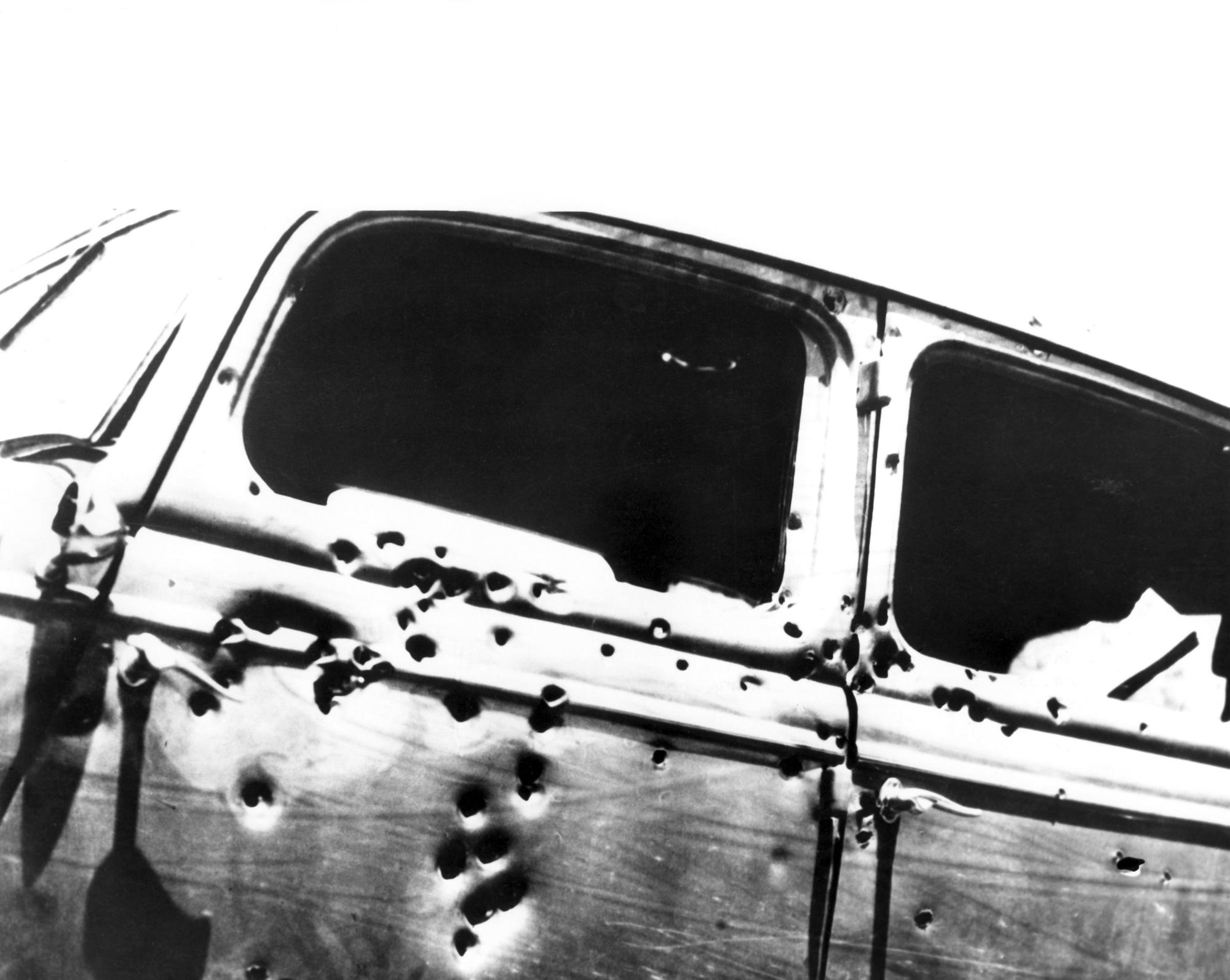 Eine Schwarz-Weiß-Aufnahme zeigt ein Auto in dem sich Einschusslöcher befinden. (Archivbild)