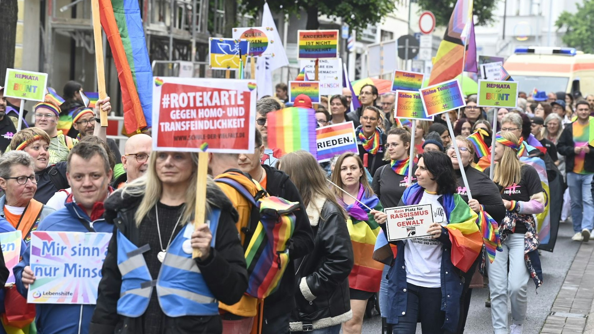 Die Pride-Parade in Euskirchen ist gestartet. Auf dem Bild sind viele Menschen zu sehen, die Banner oder Plakate in Regenbogenfarben dabeihaben.