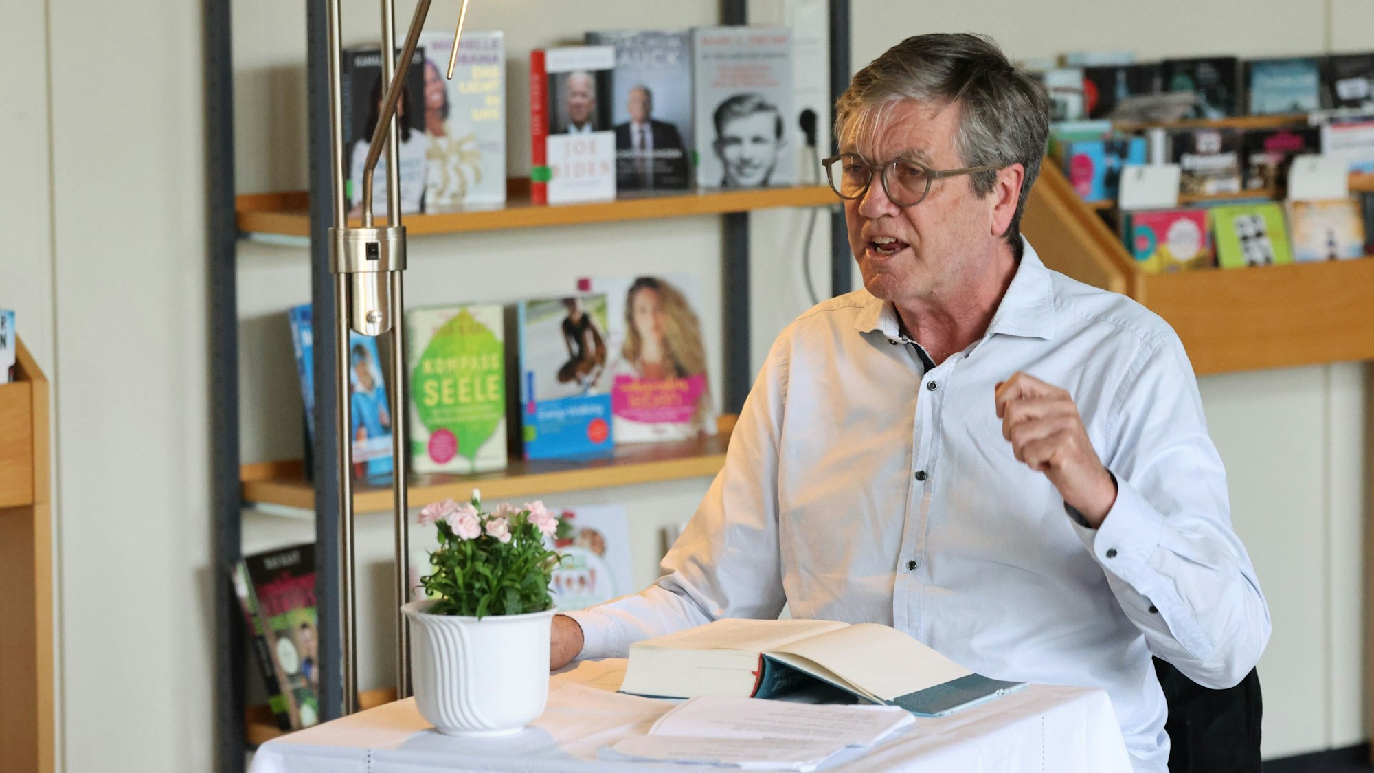 Peter Prange sitzt mit einem Buch an einem Tisch.