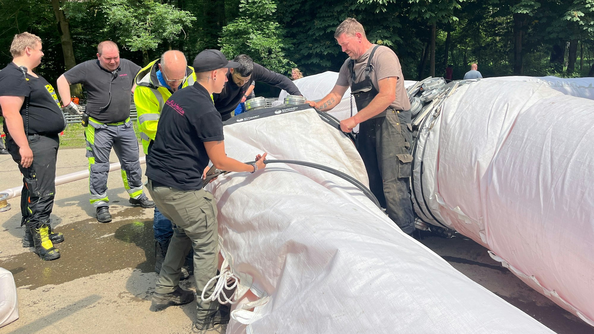 Mitarbeiterinnen und Mitarbeiter von Jola-Rent bereiten den Schlauch auf die Flutung mit Siegwasser vor.