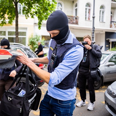 Ein Polizist stellt bei einer Hausdurchsuchung in Berlin-Kreuzberg eine Tasche in ein Fahrzeug. (Archivbild)