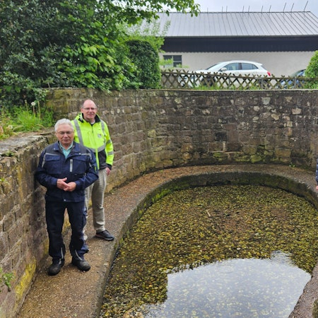 Hans Jubelius, Lothar Schatten, Hans Reiff und Peter Schildgen stehen an einem Gewässer, das von einer Mauer umgeben ist.