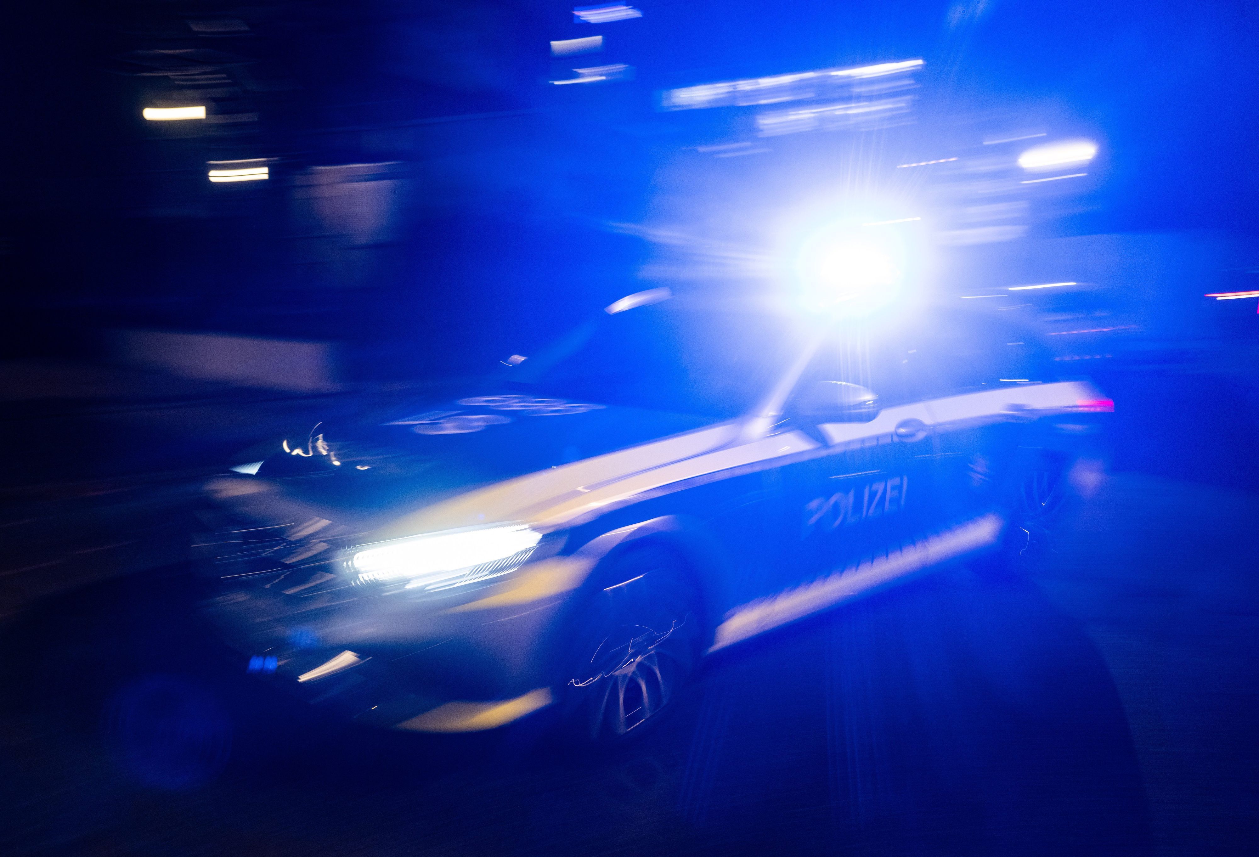 Ein Polizeifahrzeug fährt mit Blaulicht an einem Gebäude vorbei. (Symbolbild)