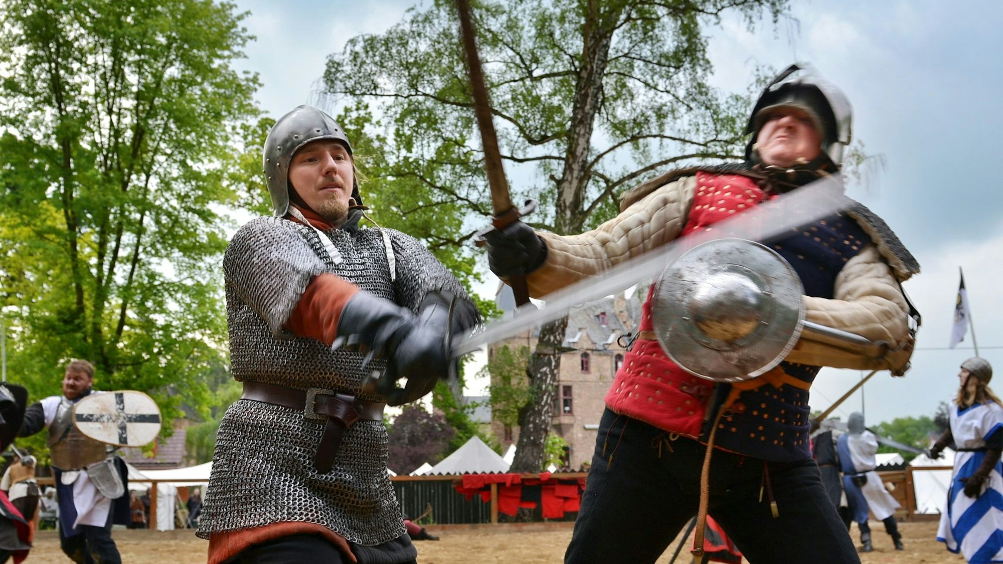Zwei Männer in mittelalterlicher Rüstung kämpfen mit Schwert und Schild gegeneinander.