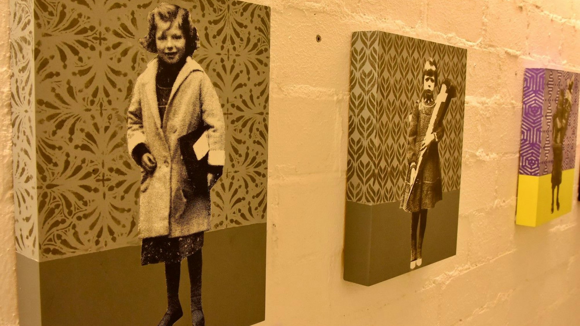 Bilder in einer Kunstausstellung. Schwarz-Weiß-Fotos von Kindern vor einem gemusterten Hintergrund.