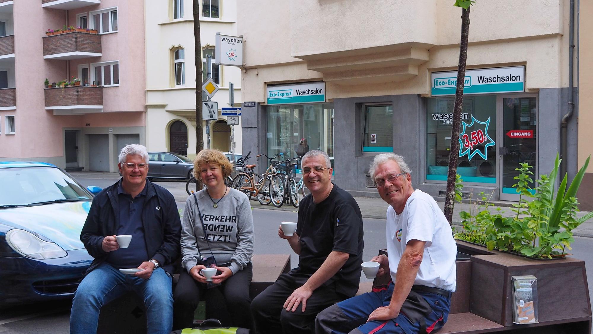 Karsten Heppner vom Bürgerverein Bayenthal-Marienburg, Sabine Müller, Matteo Specchio und Bodo Schmitt testen schon einmal das Kaffeetrinken auf Baum-Sitzbänken vor der Eisdiele.