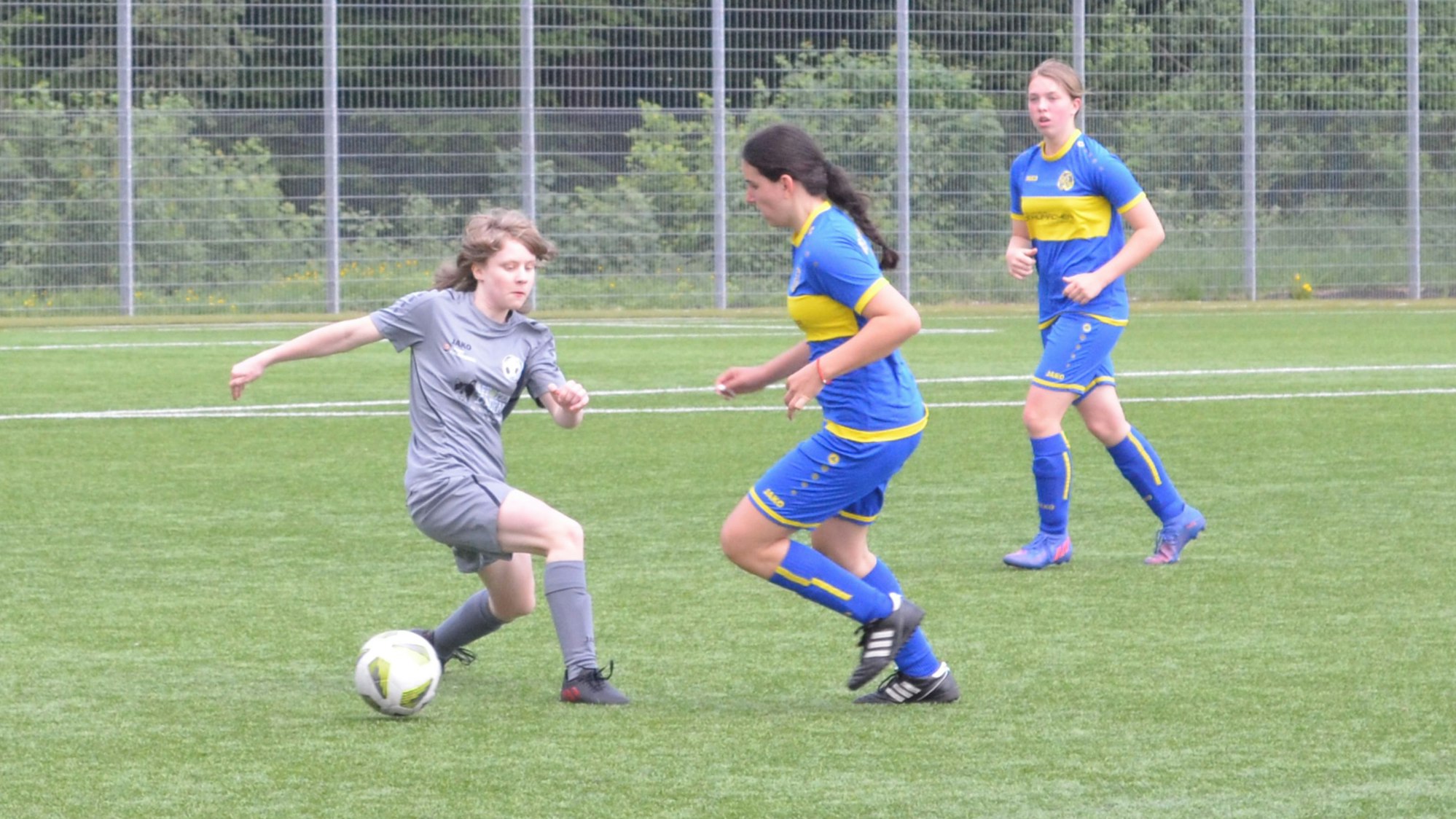 Spielsituation zweier Mädchenteams auf einem Fußballplatz.
