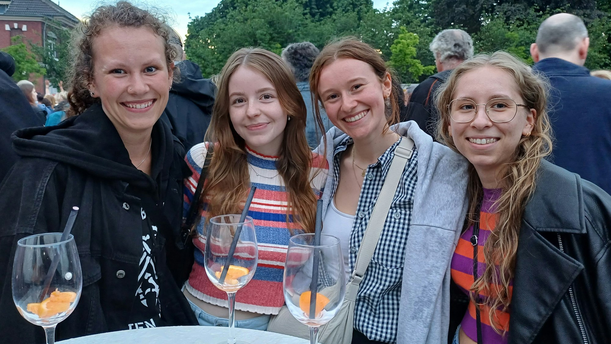 Vier junge Frauen stehen an einem Tisch mit Gläsern