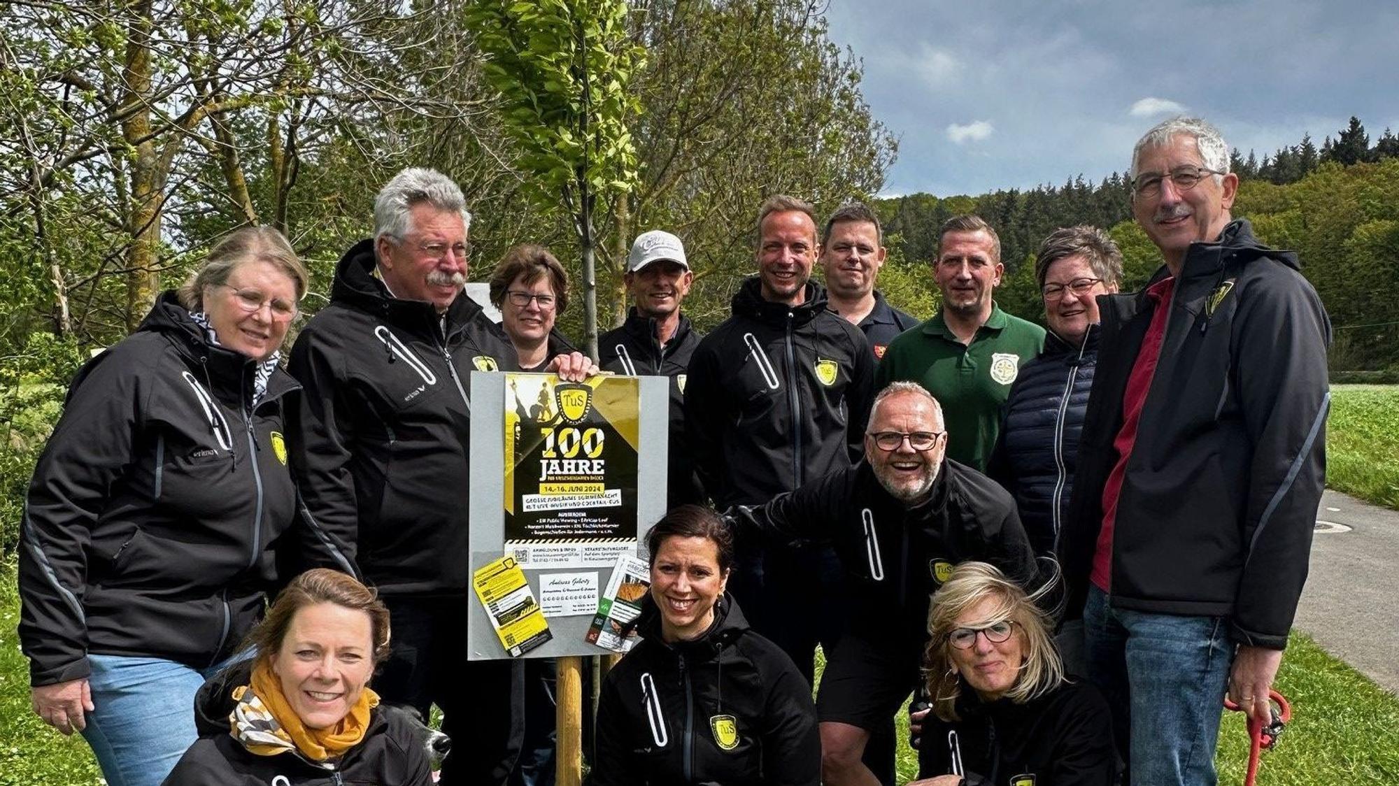 Das Bild zeigt die Vereinsmitglieder, die den Baum gepflanzt haben, um eine junge Buche verteilt.