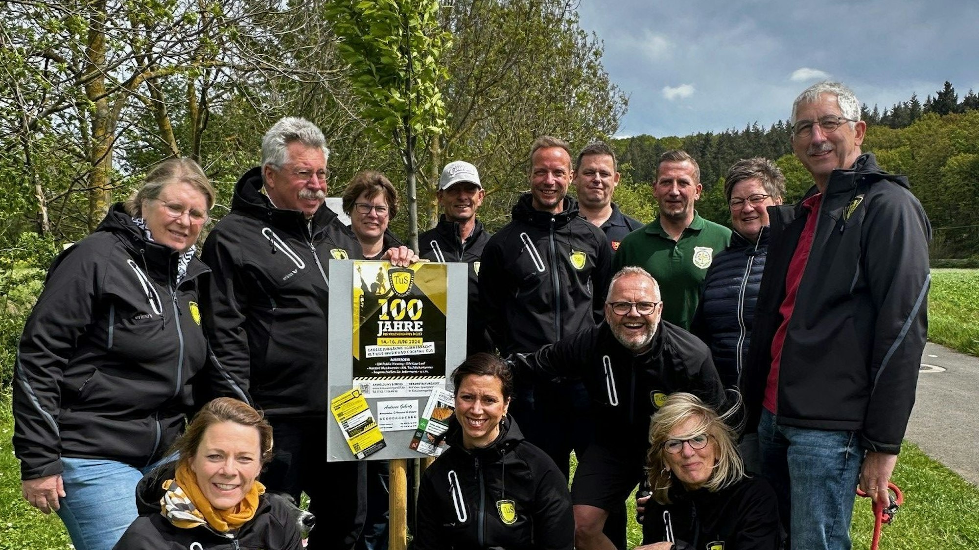 Das Bild zeigt die Vereinsmitglieder, die den Baum gepflanzt haben, um eine junge Buche verteilt.