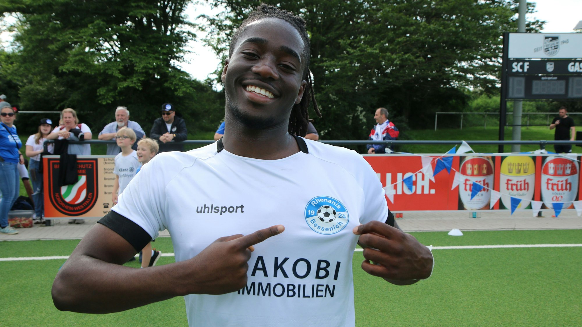 Ein Fußballer zeigt auf das Wappen auf seinem Trikot.