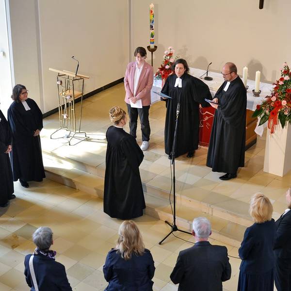 Pfarrerin Dorothee Lindenbaum steht vor Superintendentin Claudia Müller-Bück, die Presbyter bilden einen Halbkreis darum.