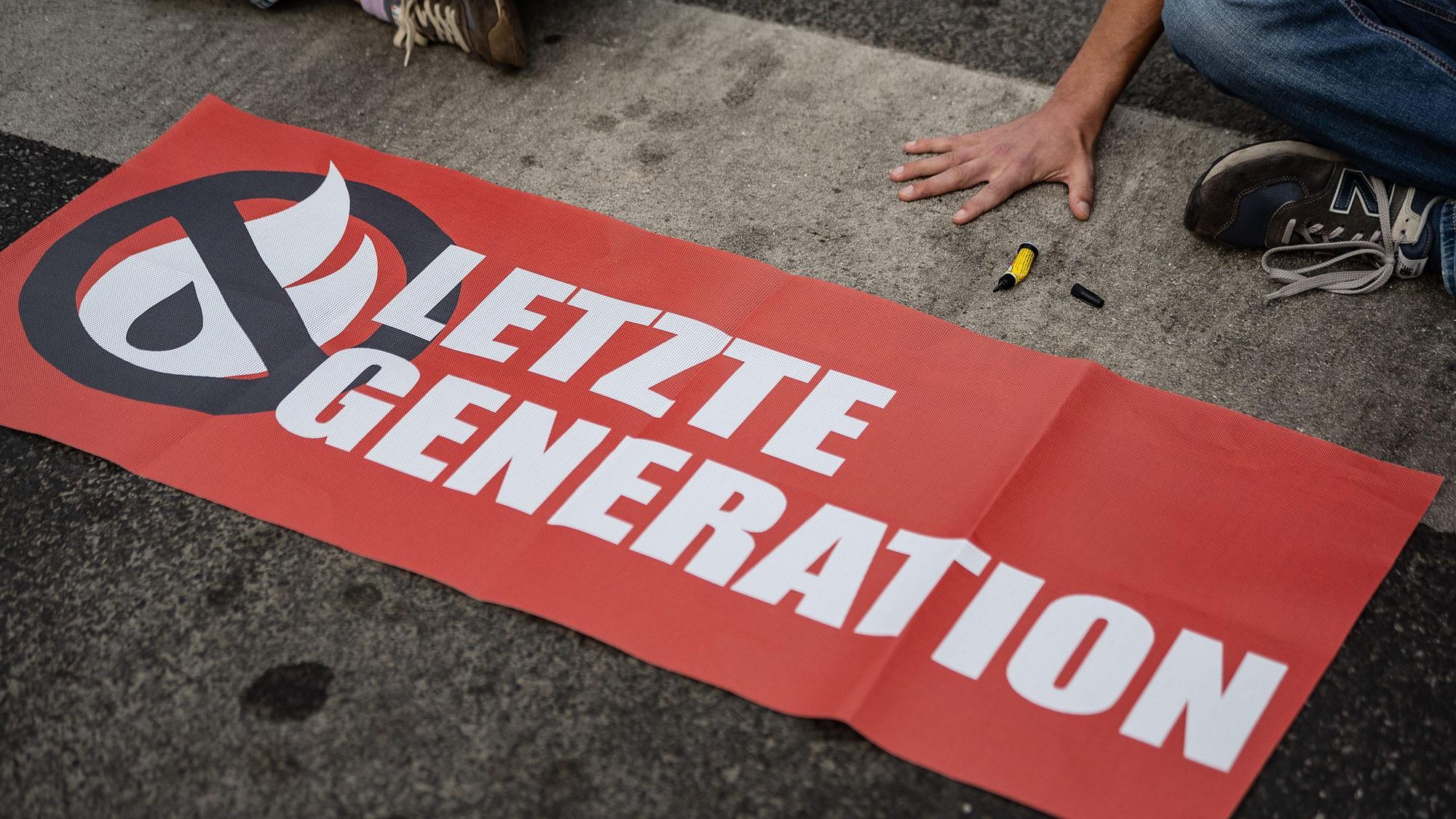ARCHIV - 16.05.2022, Niedersachsen, Göttingen: Ein Aktivist der Gruppe «Letzte Generation», der seine Hand selbst auf der Straße festgeklebt hat, blockiert eine Kreuzung am Geismar Tor.