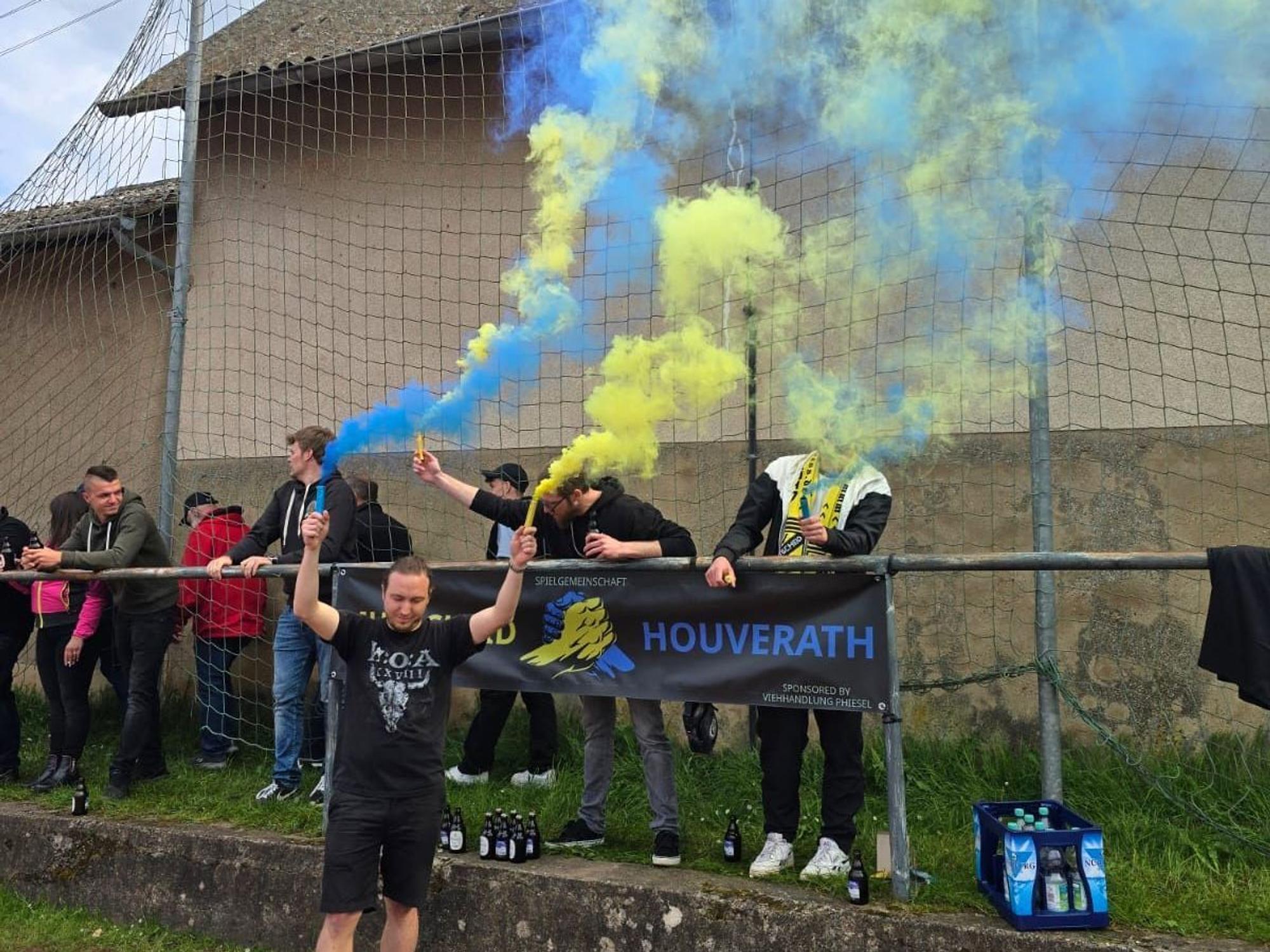 Ein Fan feiert den Klassenerhalt mit gelben und blauen Rauchfackeln.