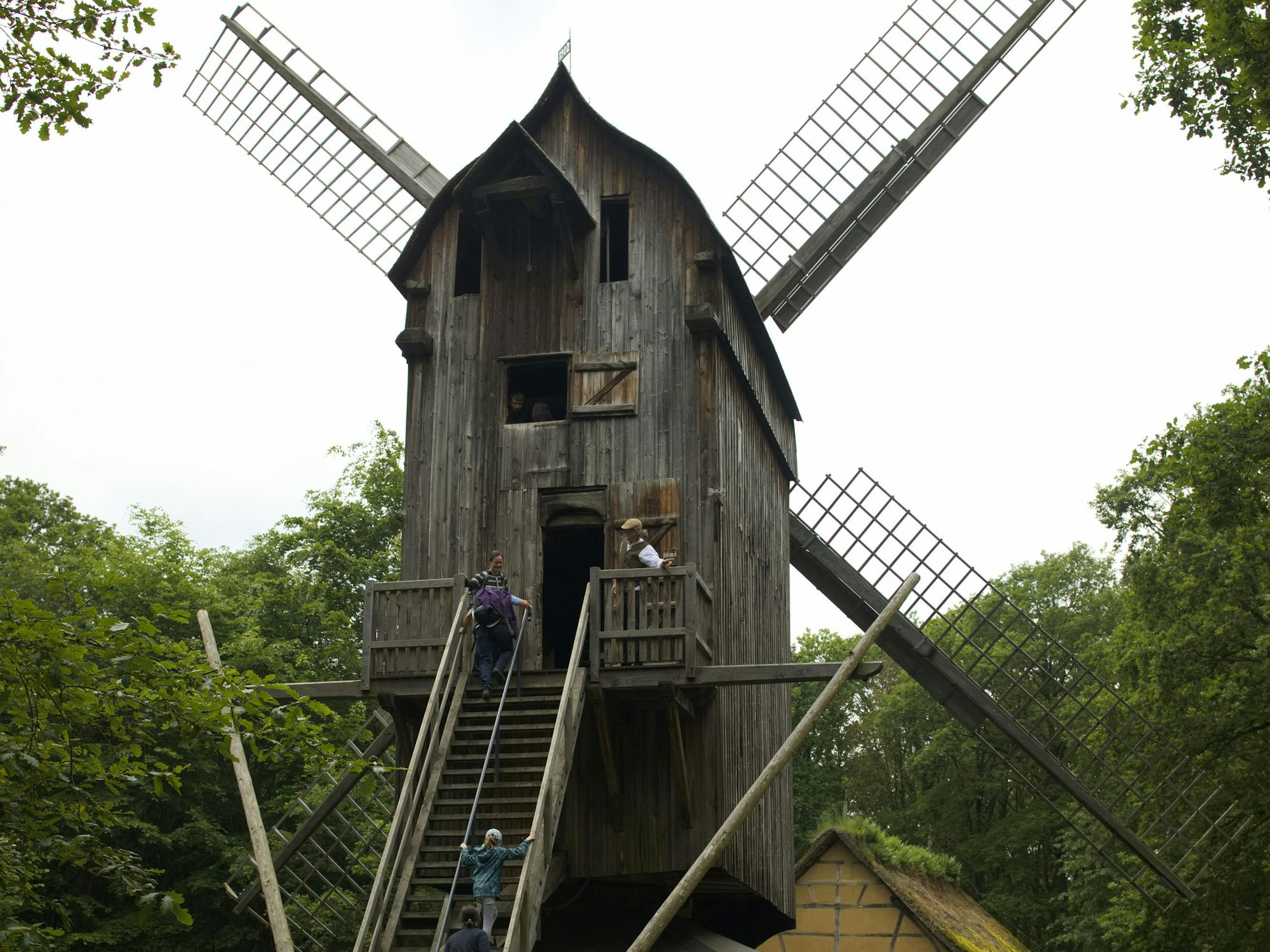 Drei Besucher steigen die Stufen der Bockwindmühle hoch.