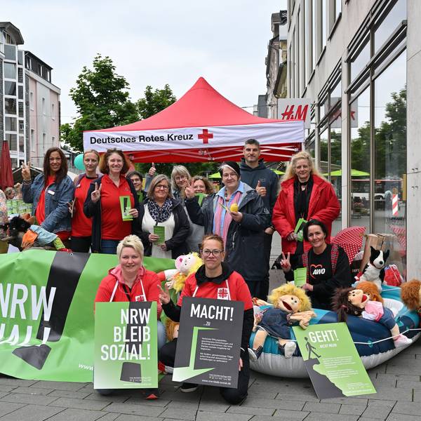 Mit Plakaten und einem großen Banner in der Hand haben sich Erzieherinnen und Erzieher für das Foto aufgestellt.