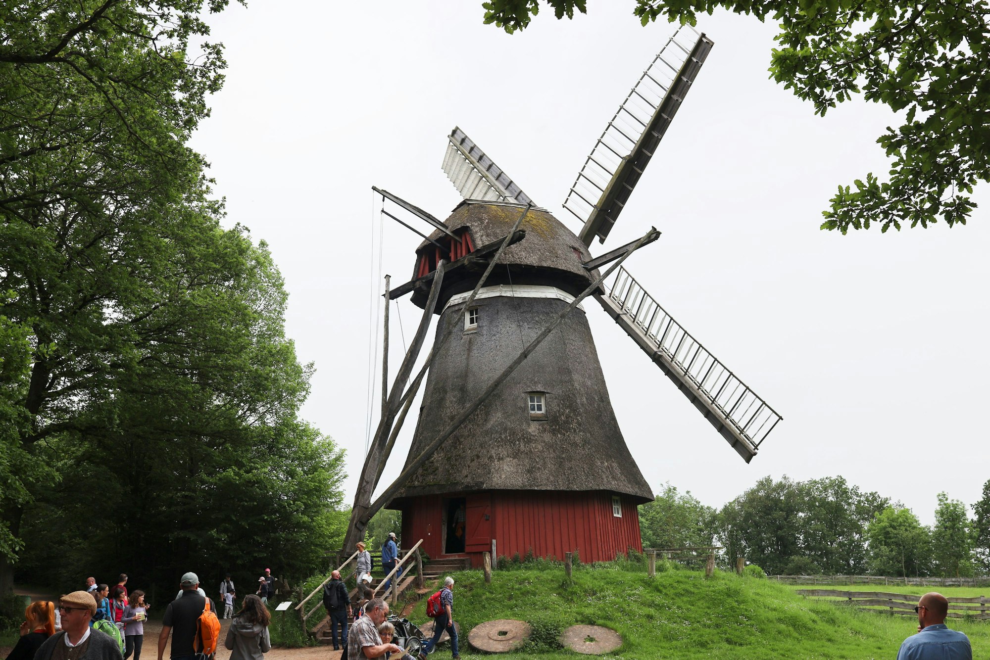 Das Bild zeigt Kappenwindmühle im LVR-Freilichtmuseum in Kommern. Mehrere Besucher stehen davor.