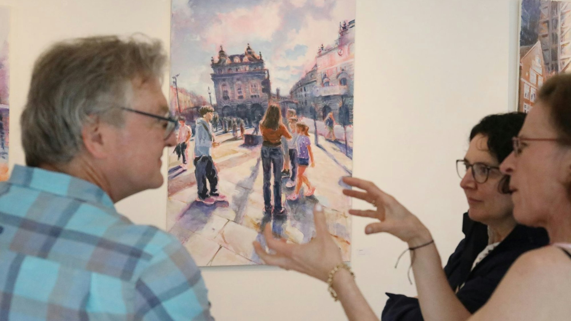 Ein Mann und zwei Frauen vor einem Bild in der Ausstellung.