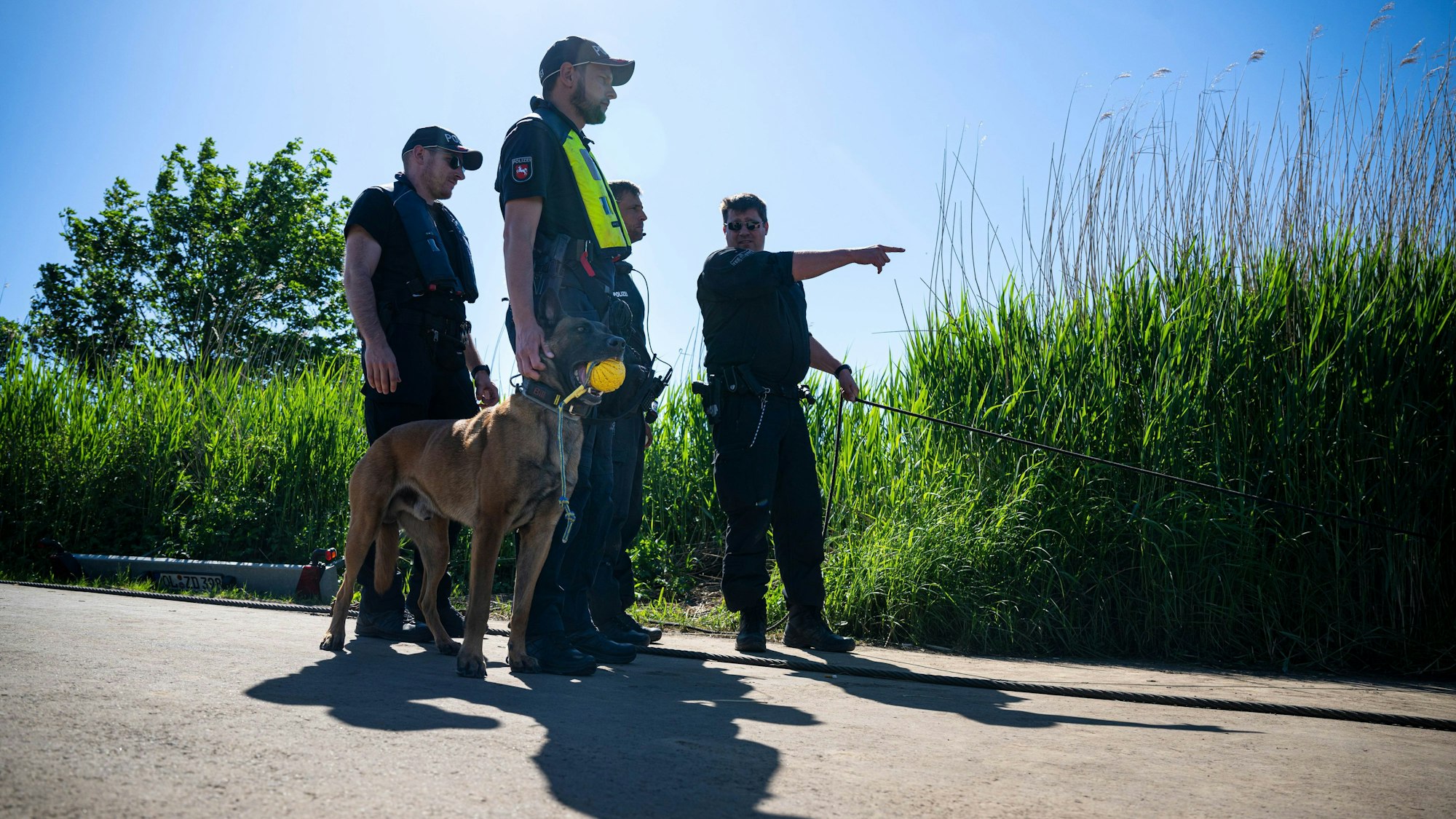 Einsatzkräfte der Polizei stehen bei der Suche nach dem vermissten Arian mit einem Spürhund an der Oste.