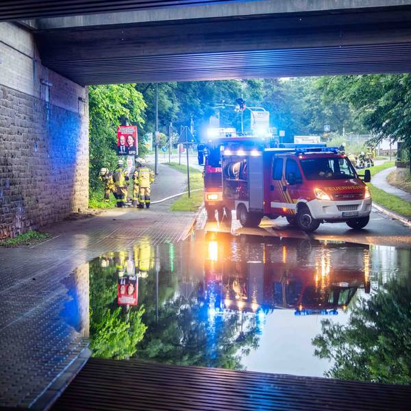 Das Bild zeigt die überflutete Unterführung. Im Hintergrund stehen zwei Feuerwehrfahrzeuge.