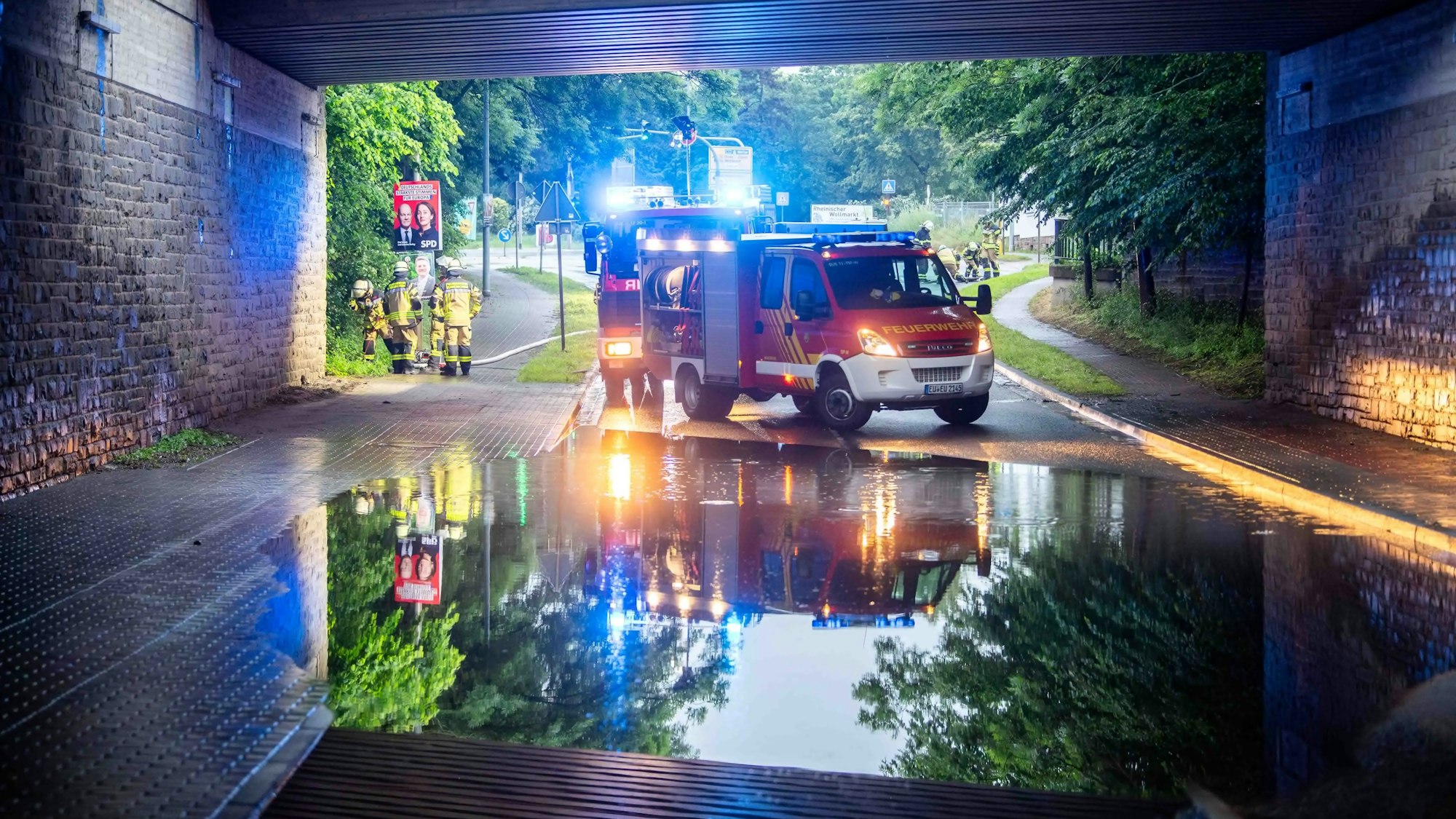 Das Bild zeigt die überflutete Unterführung. Im Hintergrund stehen zwei Feuerwehrfahrzeuge.