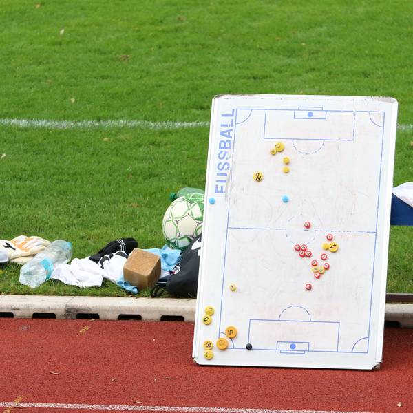 Das Bild zeigt eine Taktiktafel am Spielfeldrand. Sie lehnt an einer Auswechselbank.