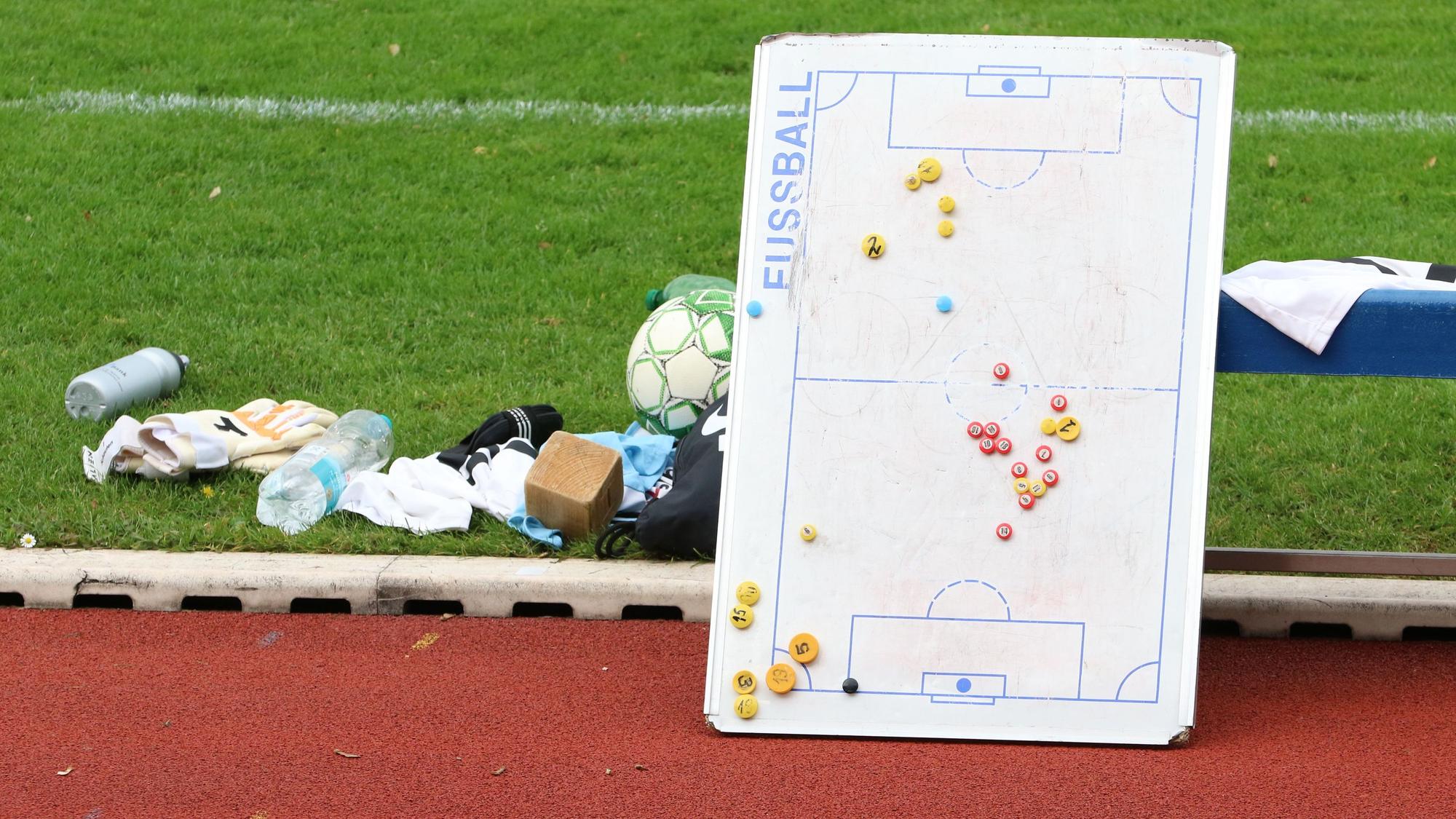 Das Bild zeigt eine Taktiktafel am Spielfeldrand. Sie lehnt an einer Auswechselbank.