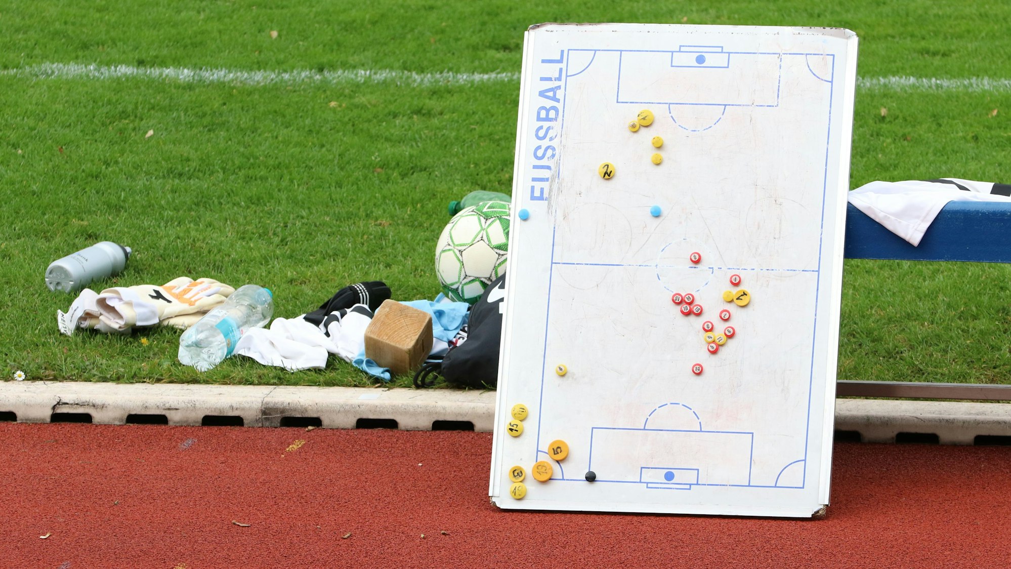 Das Bild zeigt eine Taktiktafel am Spielfeldrand. Sie lehnt an einer Auswechselbank.