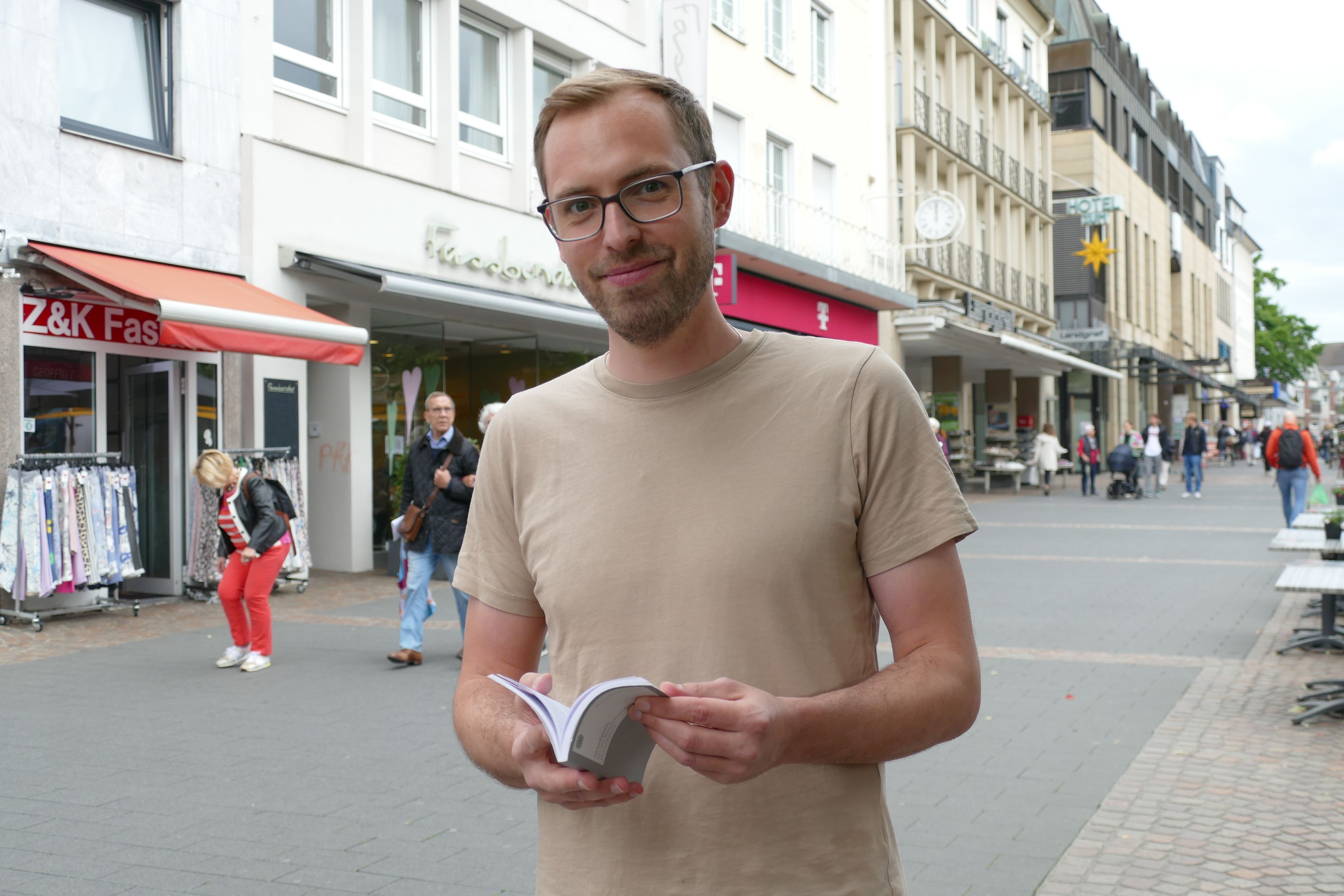 Ein Mann hält ein Grundgesetz in der Hand.