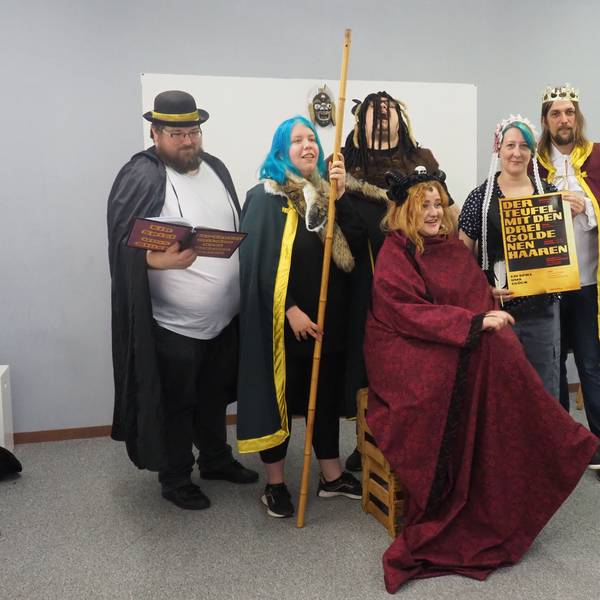 Sechs junge Erwachsene in Kostümen spielen Theater.