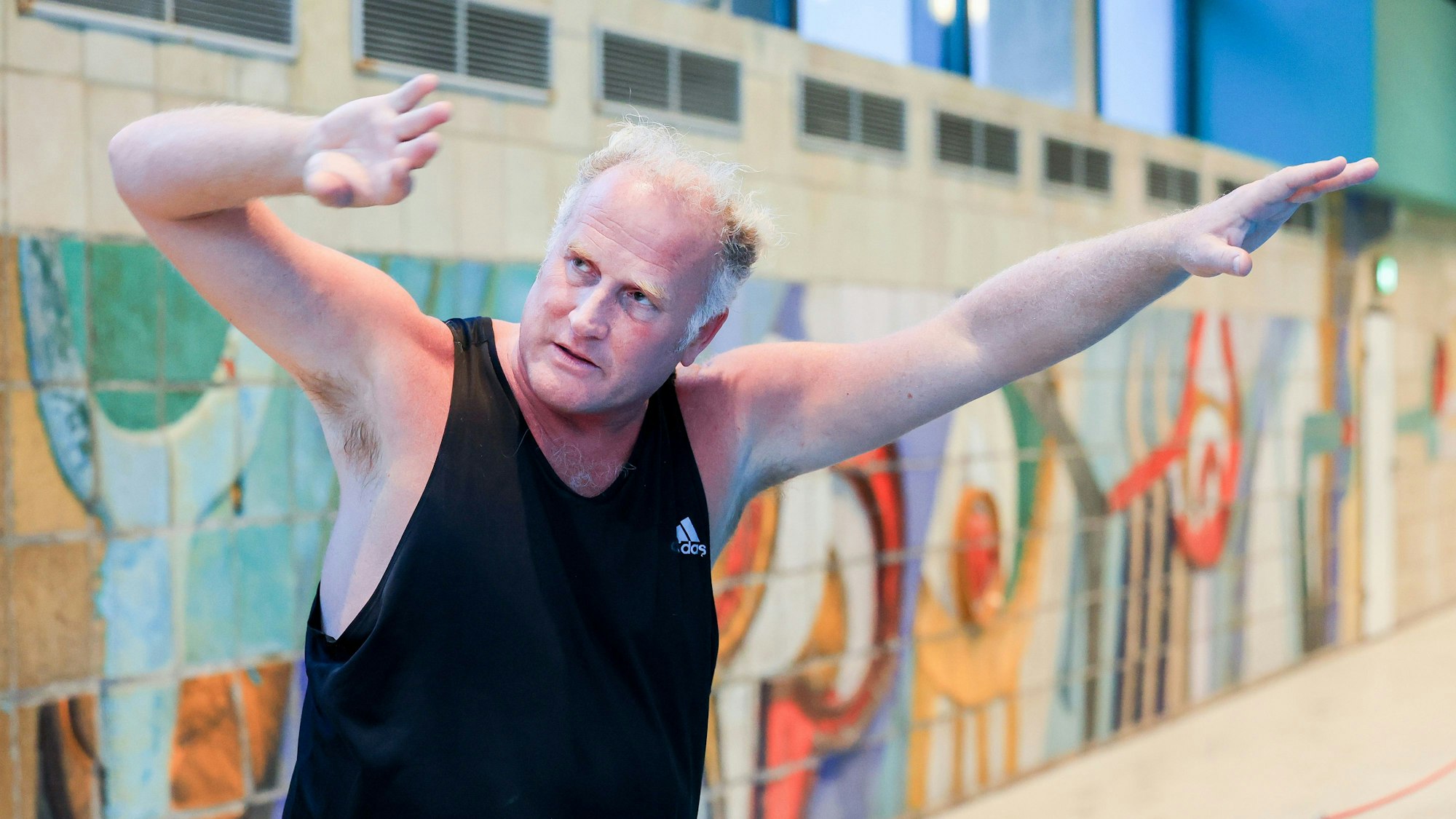 Schwimmtrainer Marco Gödde steht am Beckenrand und zeigt den Kraul-Armzug.