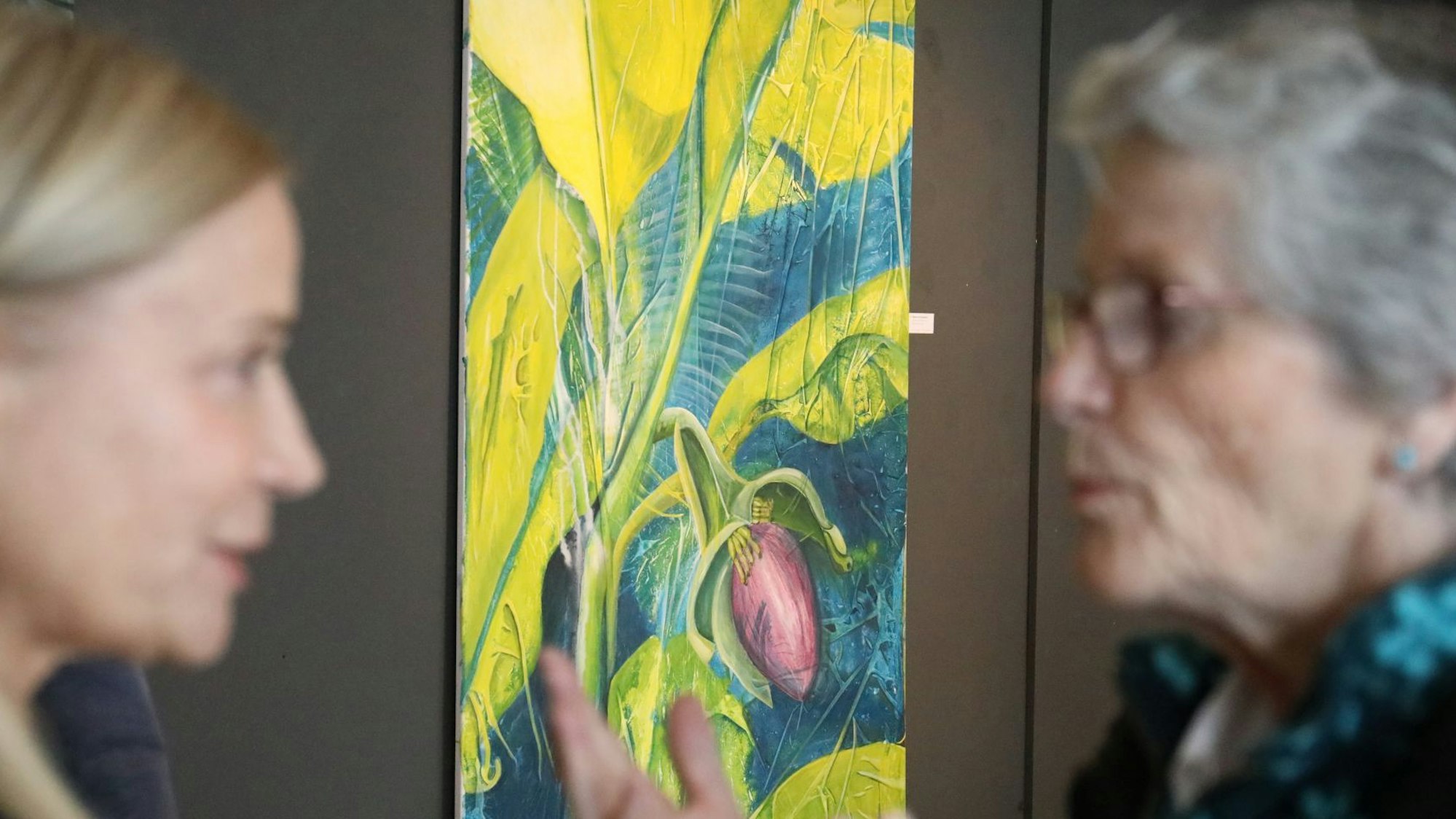 Zwei Frauen stehen links und rechts eines Kunstwerks.