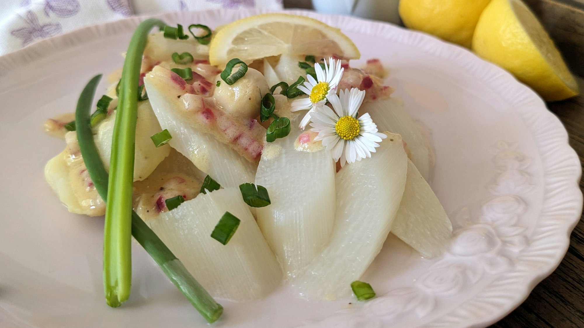 Rote Zwiebelwürfelchen und Gänseblümchen verpassen dem Spargelsalat mit erfrischender Zitrusnote ein paar frühsommerliche Farbtupfer.