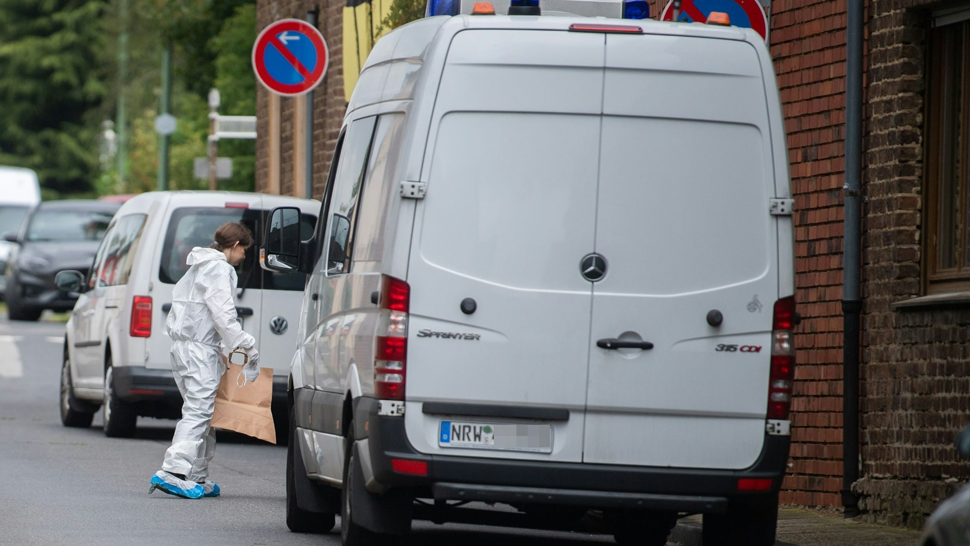 Das Bild zeigt eine Beamtin der Bonner Mordkommission am Tatort in Füssenich. Sie trägt eine Papiertüte in das Gebäude.